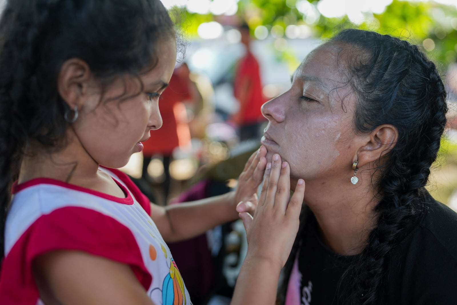 Aranza applies sunscreen on the face of her mother Angelica Flores, in Huehuetan, southern Mexico, Wednesday, Nov. 6, 2024, during a rest break from a caravan hoping to reach the country's northern border and ultimately the United States. (AP Photo/Moises Castillo)