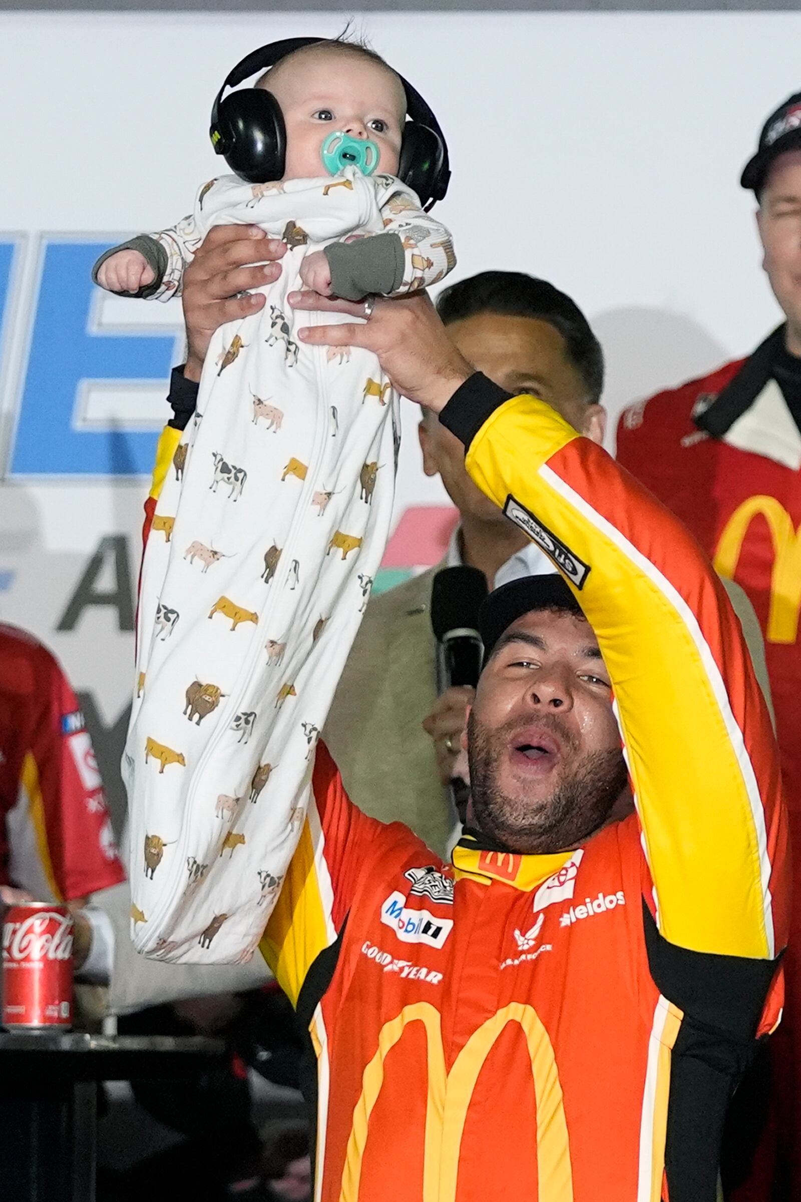 Bubba Wallace holds up his son Becks Hayden as he celebrates in Victory Lane after winning the first of two NASCAR Daytona 500 qualifying auto races at Daytona International Speedway, Thursday, Feb. 13, 2025, in Daytona Beach, Fla. (AP Photo/John Raoux)