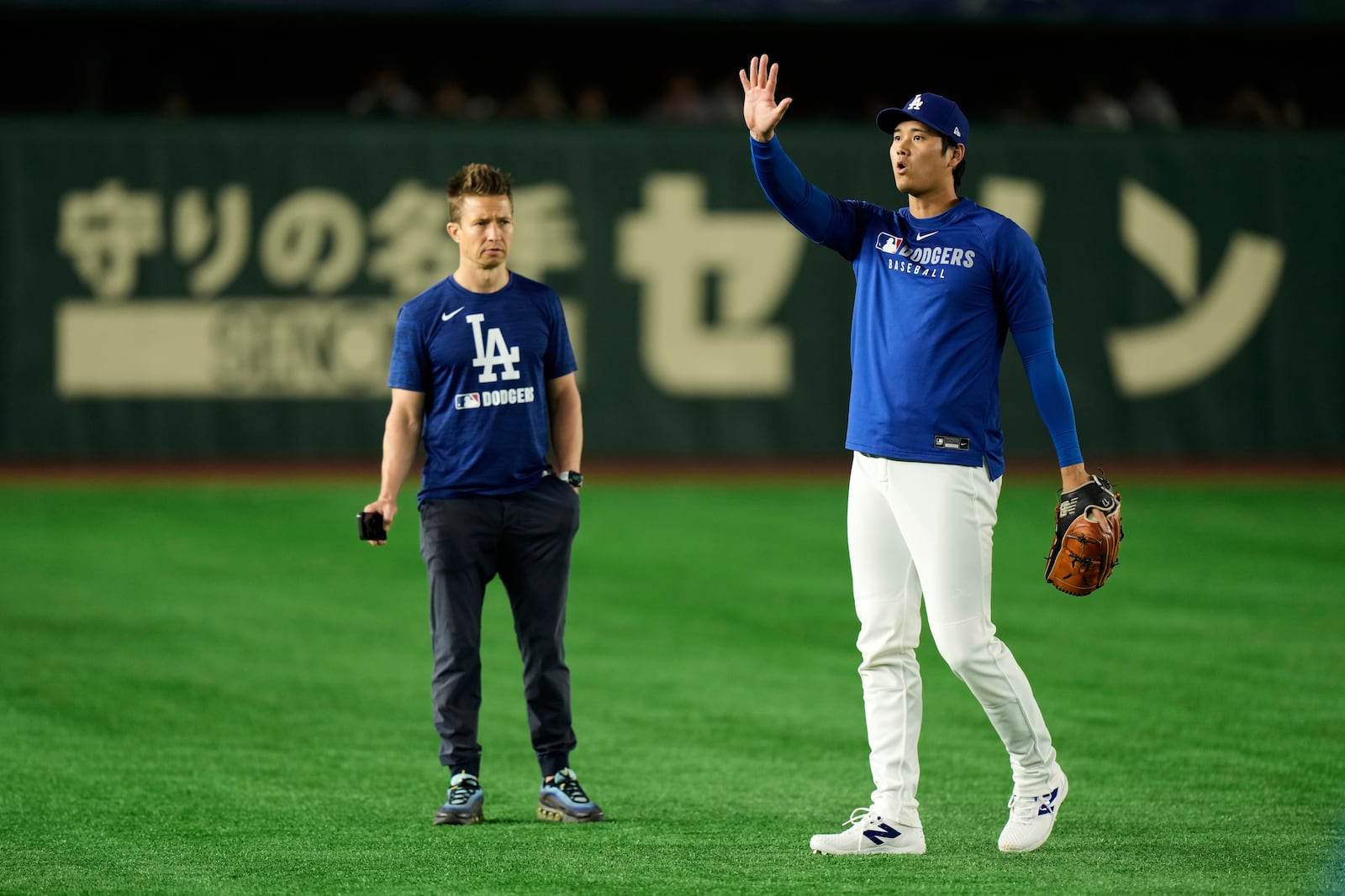 Los Angeles Dodgers' Shohei Ohtani waves from the field as he warms up before a spring training baseball game against the Yomiuri Giants in Tokyo, Japan, Saturday, March 15, 2025. (AP Photo/Eugene Hoshiko)