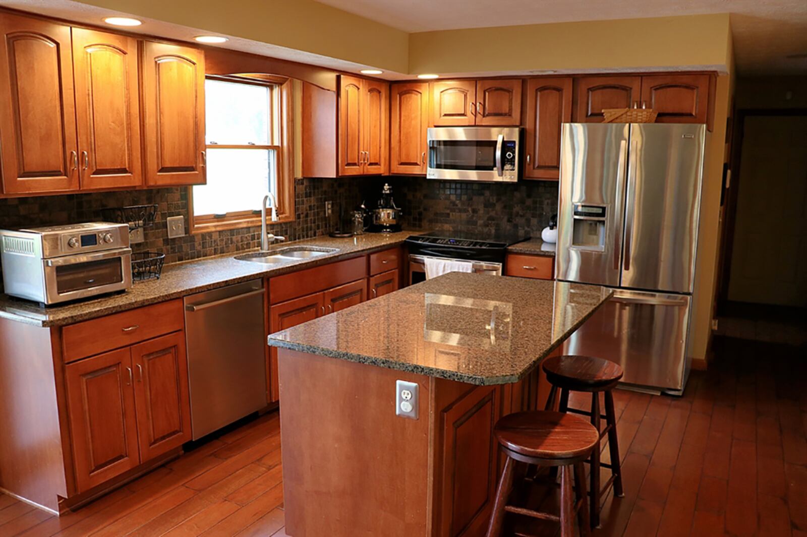 Maple cabinetry fills the kitchen and is complemented by dark granite countertops. Several of the cabinets open with roll-out shelves. The island has an extension for breakfast bar seating. CONTRIBUTED PHOTO BY KATHY TYLER