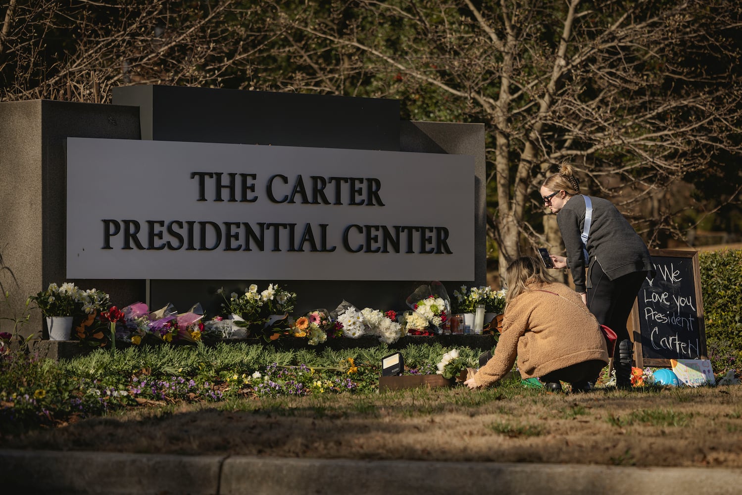 Visitors place flowers at a makeshift memorial for former President Jimmy Carter at The Carter Presidential Center in Atlanta, on Monday, Dec. 30, 2024. (Audra Melton/The New York Times)