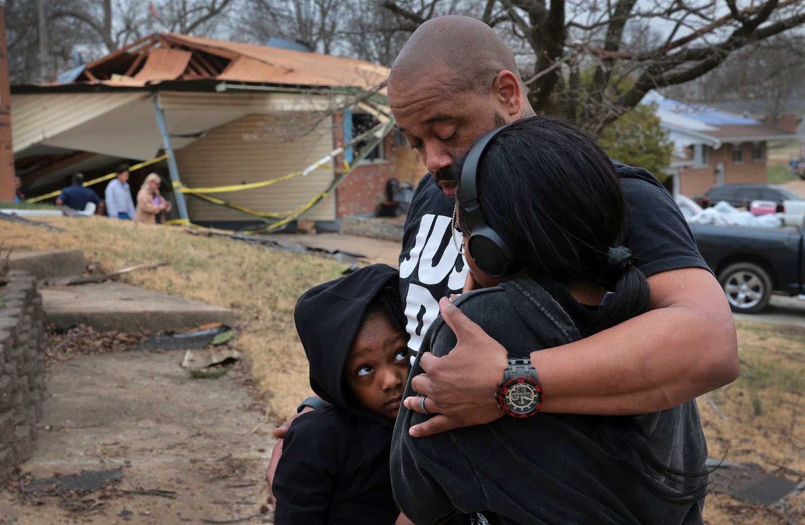 Marcus Cole embraces his daughters while standing in front of his destroyed home after a severe storm in Bridgeton, Mo., Saturday, March 15, 2025. (Robert Cohen/St. Louis Post-Dispatch via AP)