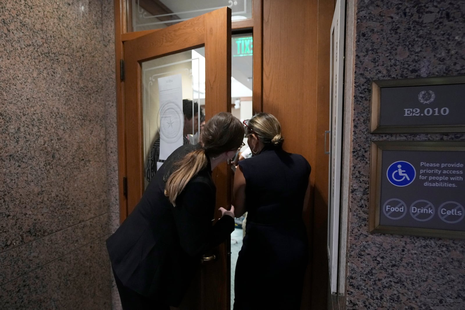 Capitol staff members look into a room where a committee is is discussing the case of death row inmate Robert Roberson, Monday, Oct. 21, 2024, in Austin, Texas. (AP Photo/Tony Gutierrez)