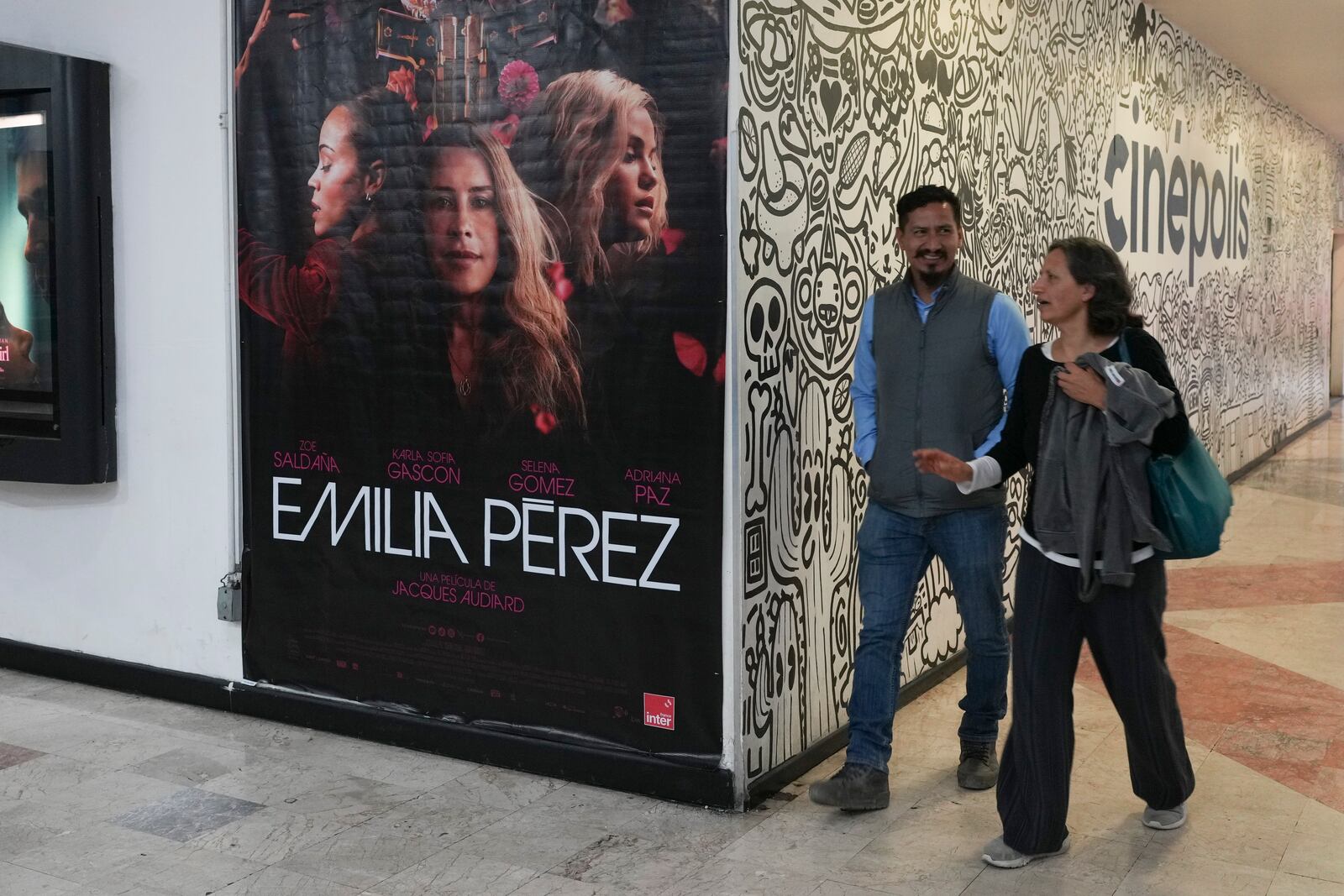 People walk past an advertisement for the film Emilia Perez, a Netflix musical about a Mexican narco trafficker who becomes a trans woman, at a movie theater in Mexico City, Thursday, Jan. 23, 2025. (AP Photo/Marco Ugarte)