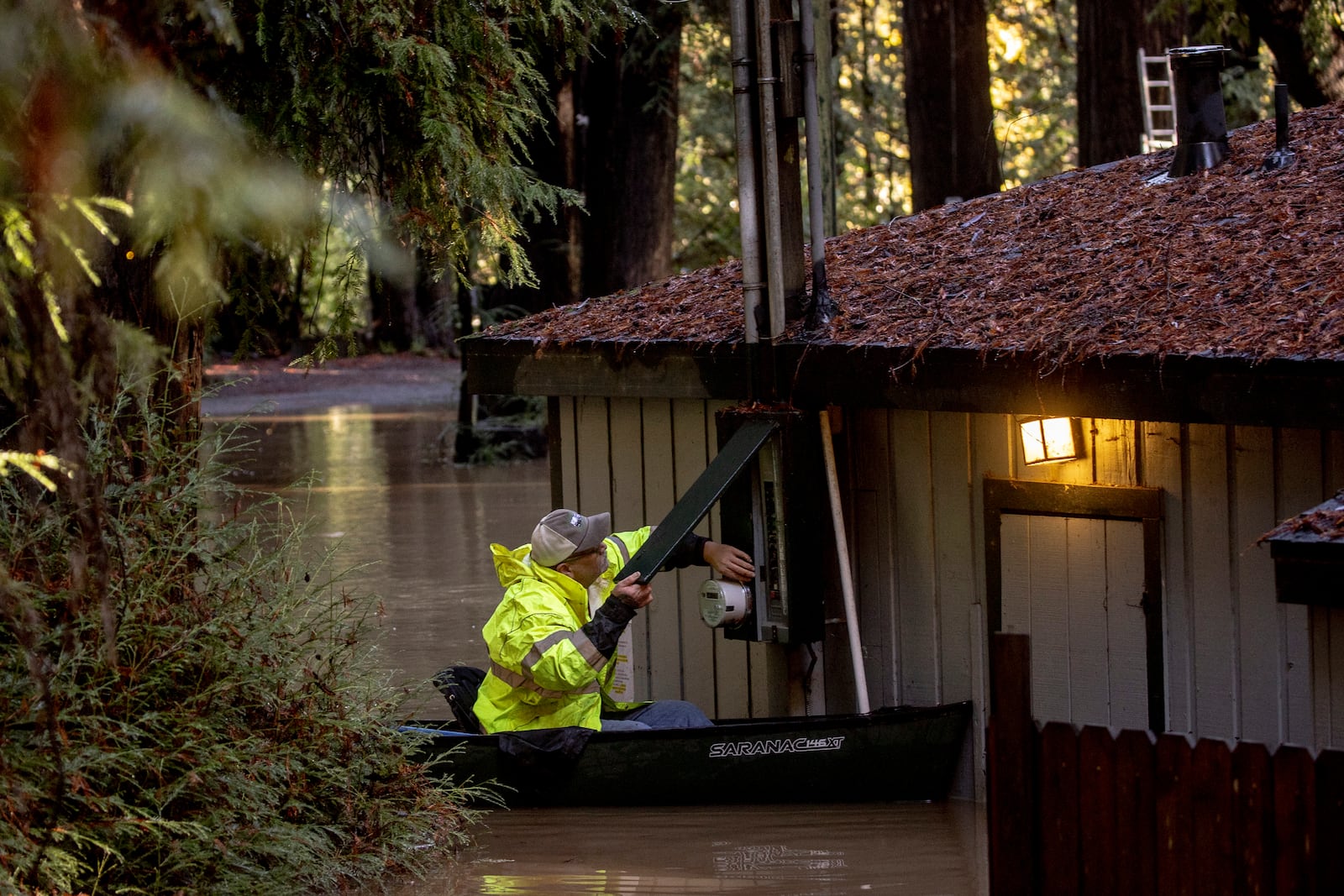 FILE - Sitting on a canoe, John Phillips works to shut down power at a flooded building at Mirabel RV Park & Campground after a storm in Forestville, Calif., Nov. 23, 2024. (Stephen Lam/San Francisco Chronicle via AP)