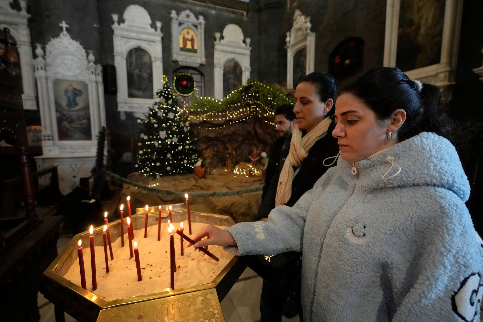 A Syrian Christians woman lights a candle during the first Sunday Mass since Syrian President Bashar Assad's ouster, at Mariamiya Orthodox Church in old Damascus, Syria, Sunday, Dec. 15, 2024. (AP Photo/Hussein Malla)