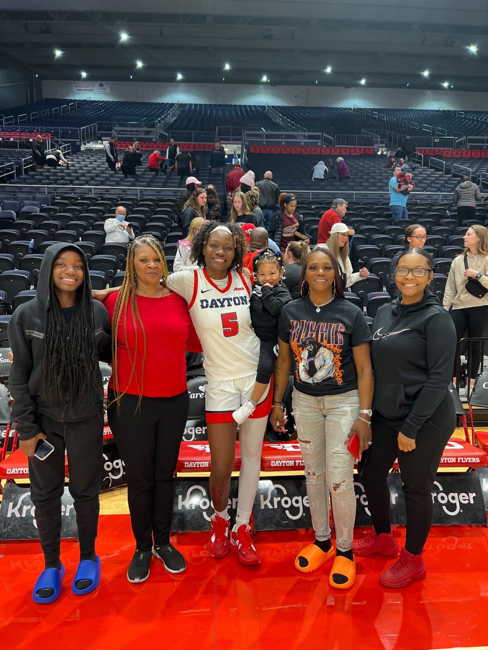 Dayton forward Arianna Smith, who played her first game for Flyers Thursday night after transferring from Indiana State and recovering from a knee surgery eight months ago, stands courtside at UD Arena with her family from Columbus. From left< sister Ajanae, grandmother Lashon Canada, Arianna holding 3-year-old niece Alayah, mother Aisha and sister (and Alayah’s mom) Alicia. Arianna’s third sister, Alexia, was playing for the University of Virginia against Georgia Tech on Thursday. CONTRIBUTED