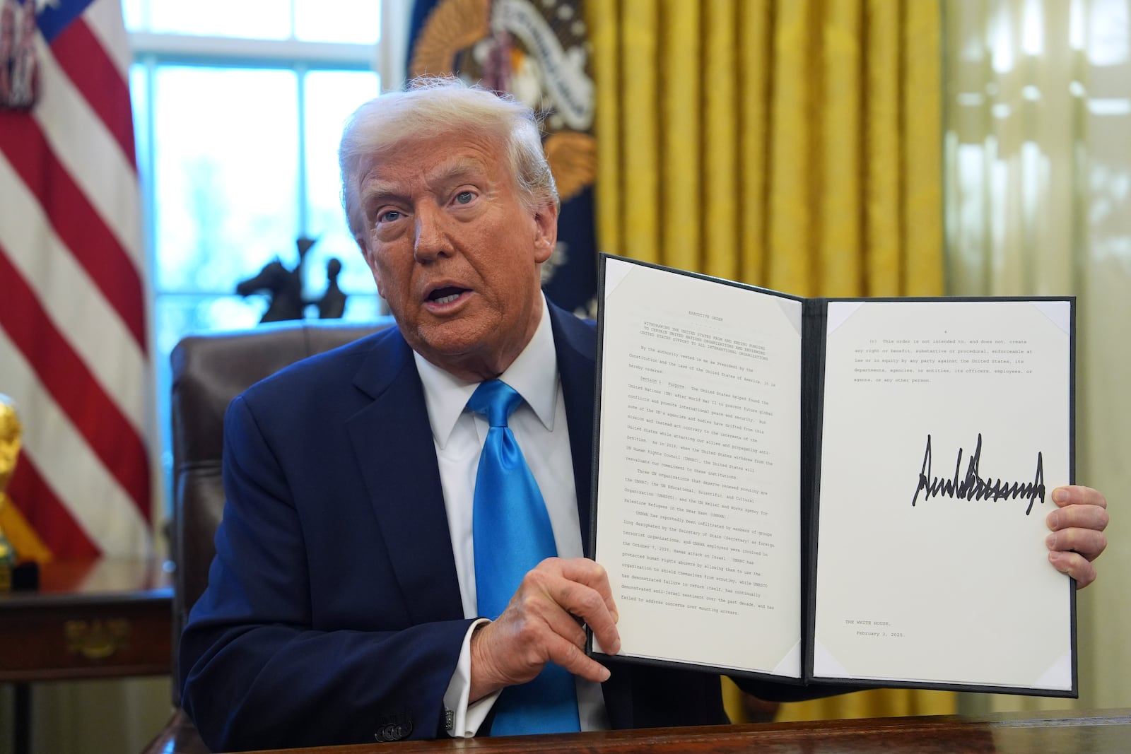 President Donald Trump holds an executive order regarding withdrawing from the United Nationals Human Rights Council in the Oval Office of the White House, Tuesday, Feb. 4, 2025, in Washington. (AP Photo/Evan Vucci)