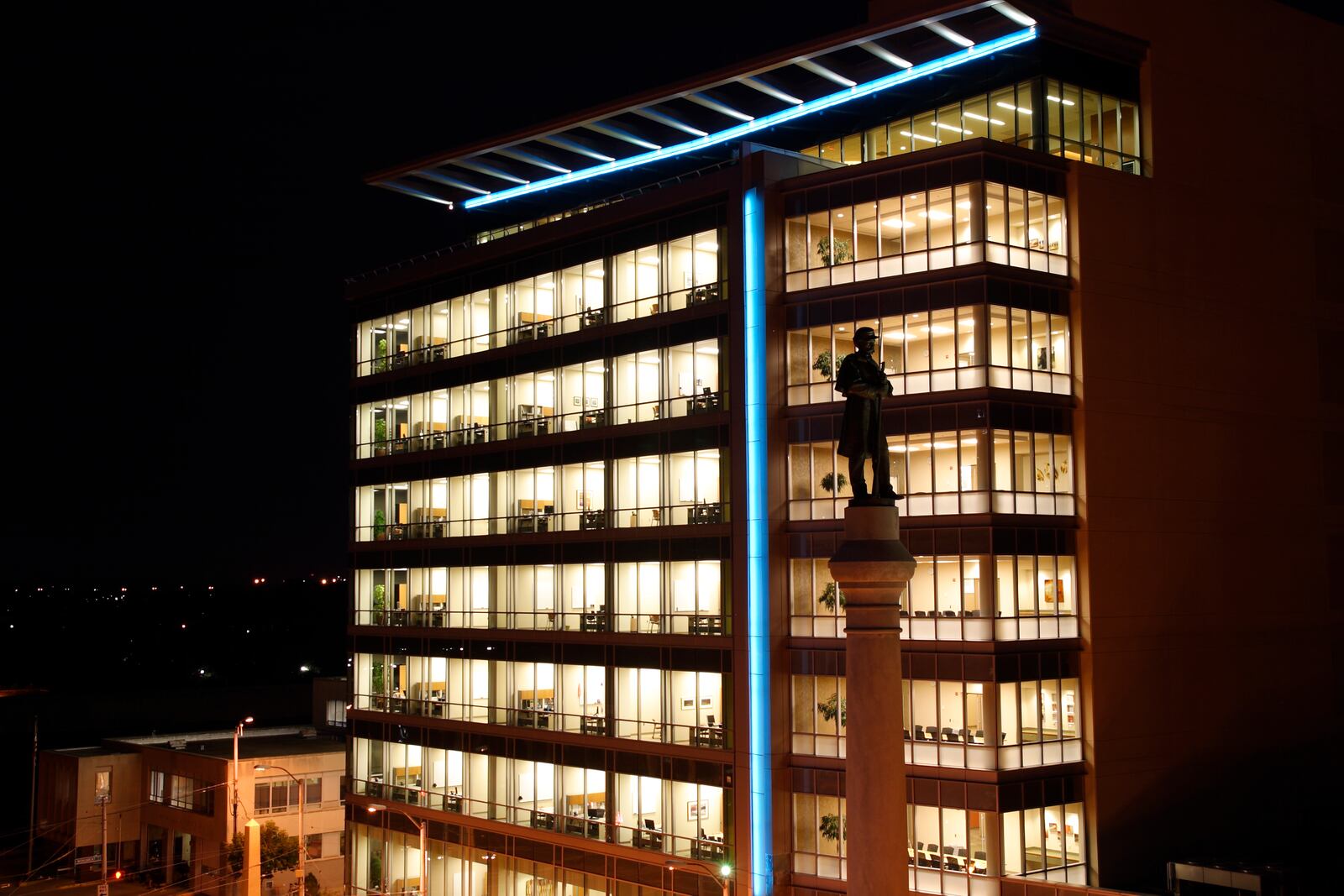 The top of Private Fair Square, an island on Main Street near Monument Avenue is silhouetted against the CareSource Building with extra lighting during First Friday in downtown Dayton, Friday, August 5, 2011. According to DDN writer James Cummings, 'this statue was modeled for Civil War veteran George Washington Fair, a bricklayer born in Dayton in 1834.'