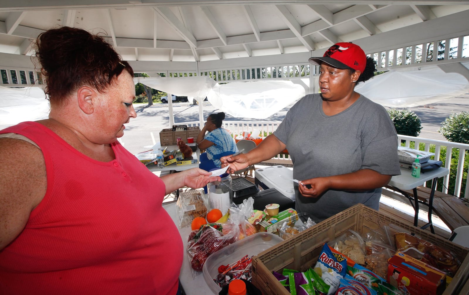 Neah Rainey, right, has been handing out home-cooked meals and personal items to tornado survivors. She gave help to hundreds a day right after the storm hit Memorial Day. And just about every day she can still be found at the gazebo at Shiloh Church with her mother, Zola Williams, helping out families, including Cassie Pepper, who stopped by for help recently. CHRIS STEWART / STAFF