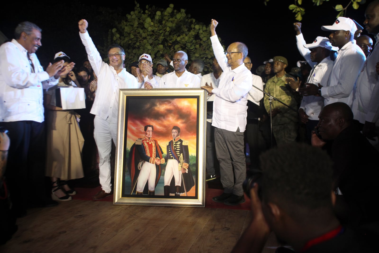 Colombia's President Gustavo Petro, left, and Leslie Voltaire, the. president of Haiti's Transitional Council, raise their fists with a painting of Simon Bolivar and Alexandre Petion in Jacmel, Haiti, Wednesday, Jan. 22, 2025. (AP Photo/Patrice Noel)