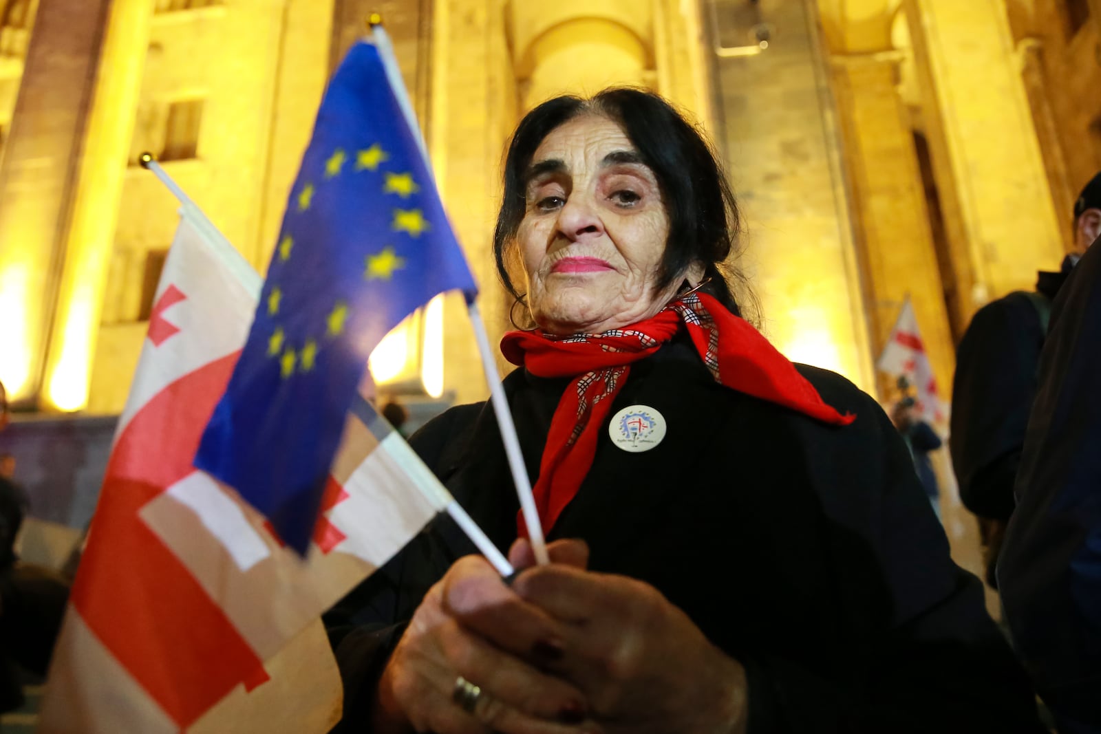 A woman holds a Georgian national and an EU flags during an opposition protest agains the results of the parliamentary election in Tbilisi, Georgia, Monday, Oct. 28, 2024. (AP Photo/Zurab Tsertsvadze)