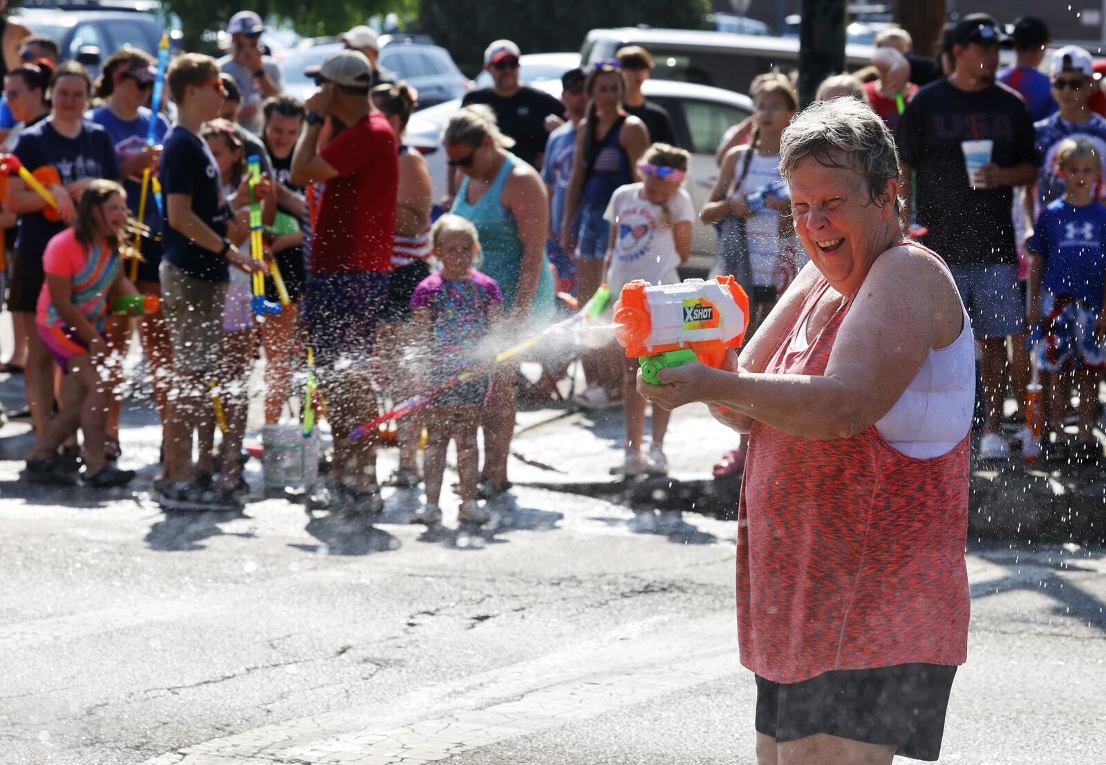 Sandy Walters gets in on the water fight action during Franklin's Independence Day Parade, known as "The Wettest Parade in Ohio", Tuesday, July 4, 2023 on Main Street in Franklin. Wet zones are set up at each intersection for a friendly water fight with many parade floats and fire trucks blasting water at bystanders. NICK GRAHAM/STAFF