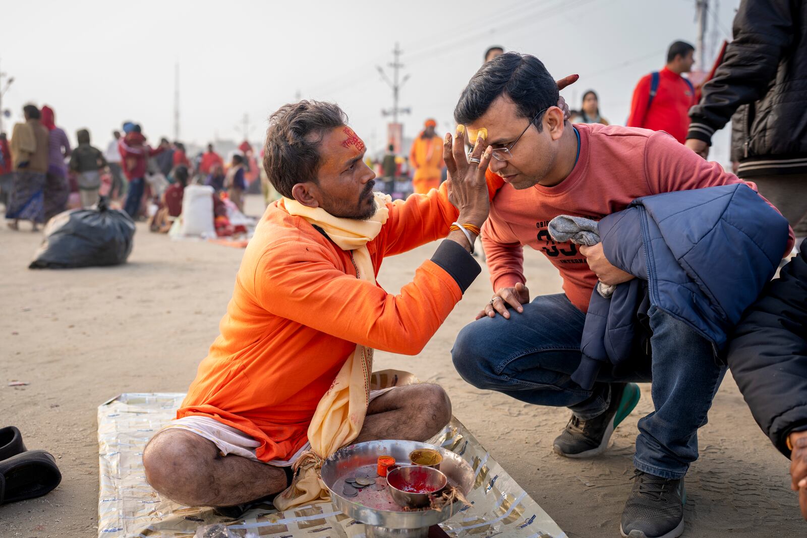 Shiv Kumar Pandey puts a sacred mark on a Hindu devotee's forehead at the confluence of the Ganges, the Yamuna, and the Saraswati rivers during the 45-day-long Maha Kumbh festival in Prayagraj, India, Tuesday, Jan. 14, 2025. (AP Photo/Ashwini Bhatia)