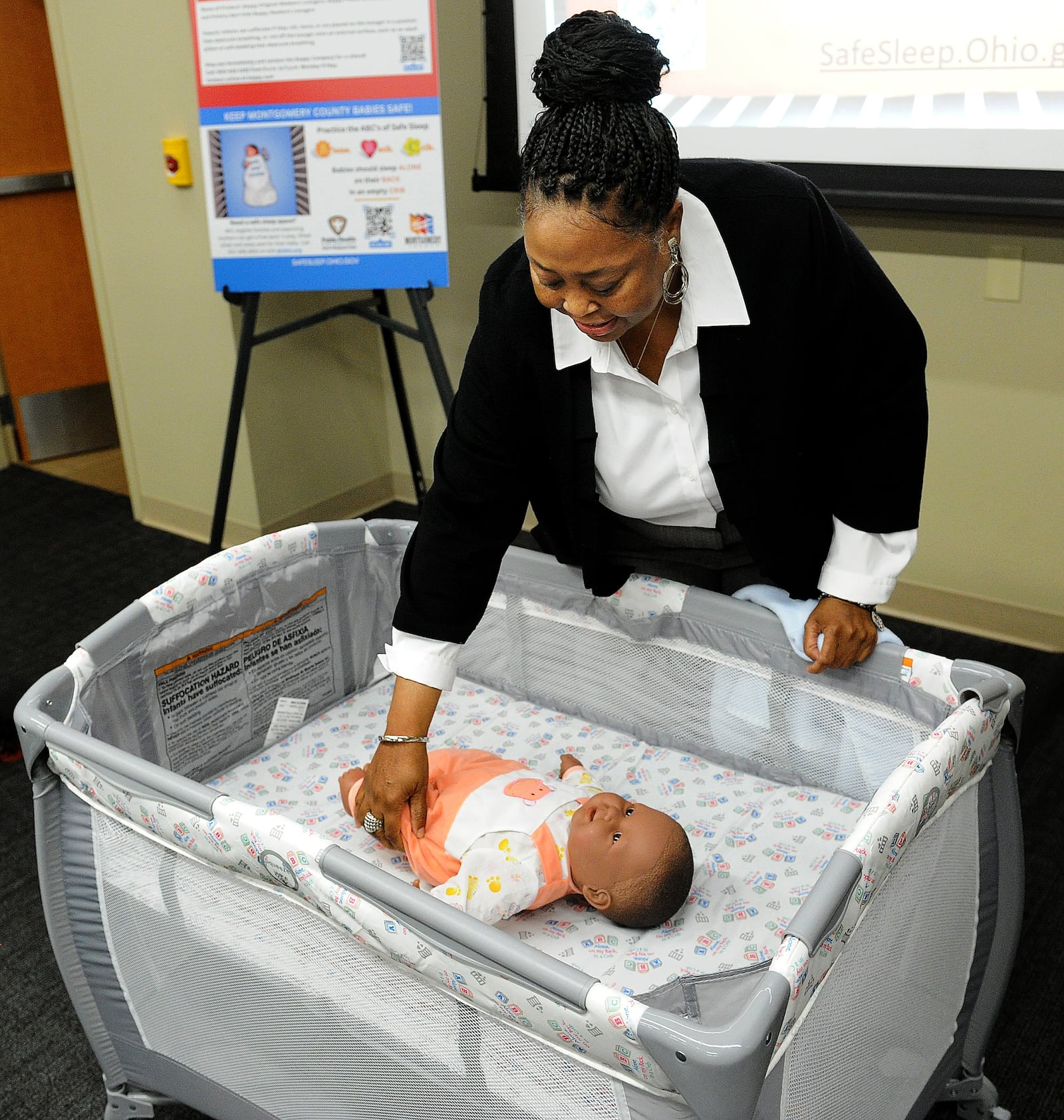 Community Health Advocate Angela Grayson demonstrates the the way to help babies sleep safer during a press conference Wednesday, May 10, 2023 on infant mortality in Montgomery County. Parents are asked to remember the ABC's of safe baby sleep: Alone, Back and Crib. MARSHALL GORBY\STAFF