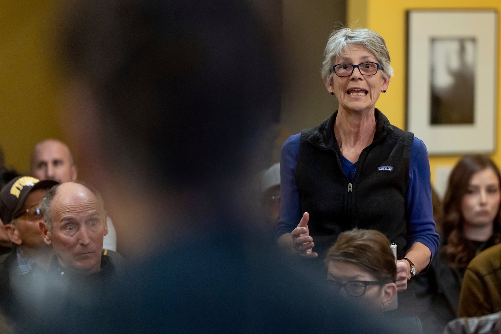 Resident Catherine DeVries, right, makes a comment critical of cuts to USAID as Rep. Harriet Hageman, R-Wyo., in foreground, holds a town hall meeting on Friday, March 14, 2025, in Evanston, Wyo. (AP Photo/Spenser Heaps)