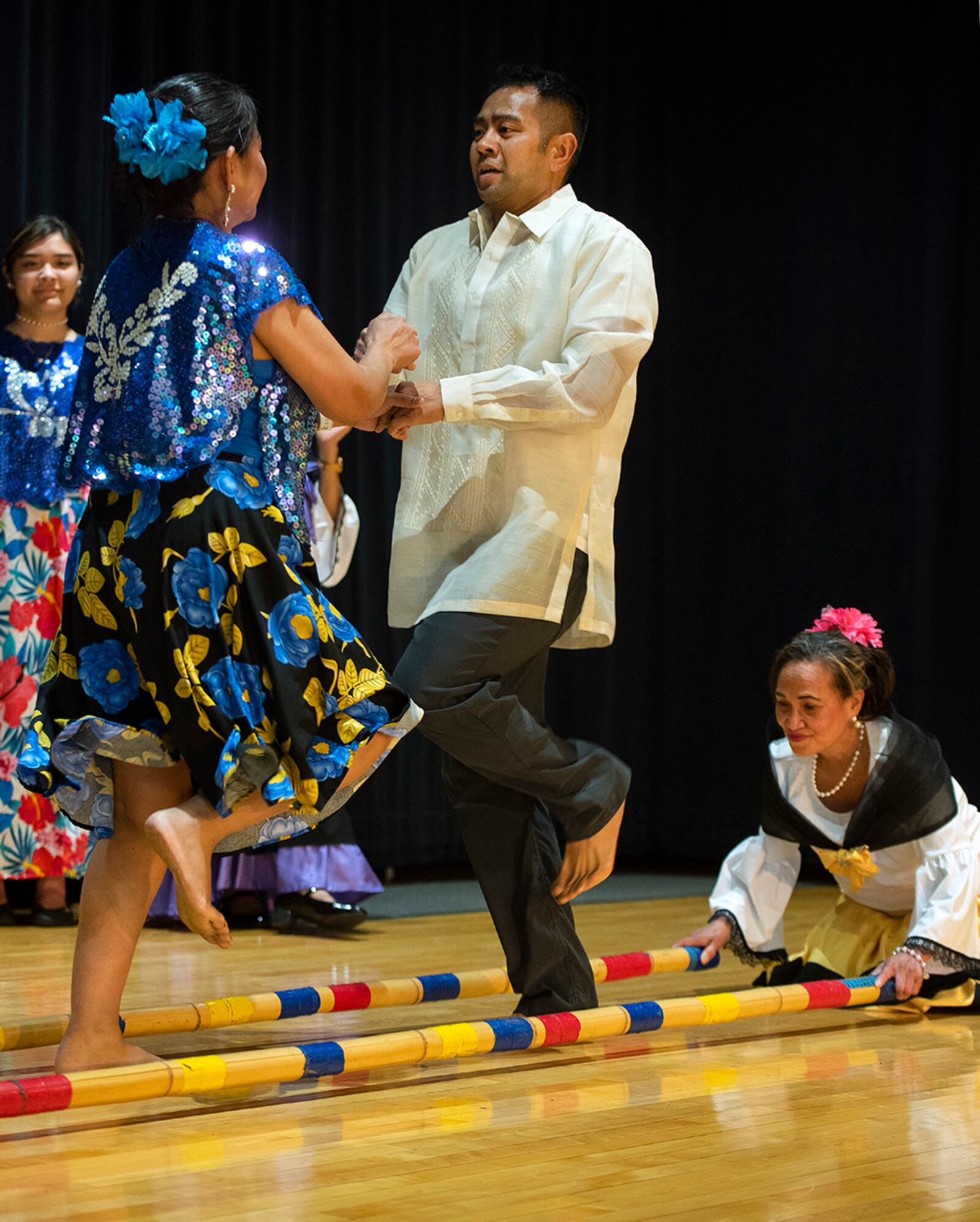 Master Sgt. Eric Natalicio, 88th Force Support Squadron, joins dancers with the Philippine-American Society of Greater Dayton in a traditional bamboo dance during a luau on Wright-Patterson Air Force Base May 27. The dance involved dancers moving between a pair of bamboo rods that are being banged together rhythmically. Mistakes in timing would result in ankles getting hit. U.S. AIR FORCE PHOTO/R.J. ORIEZ