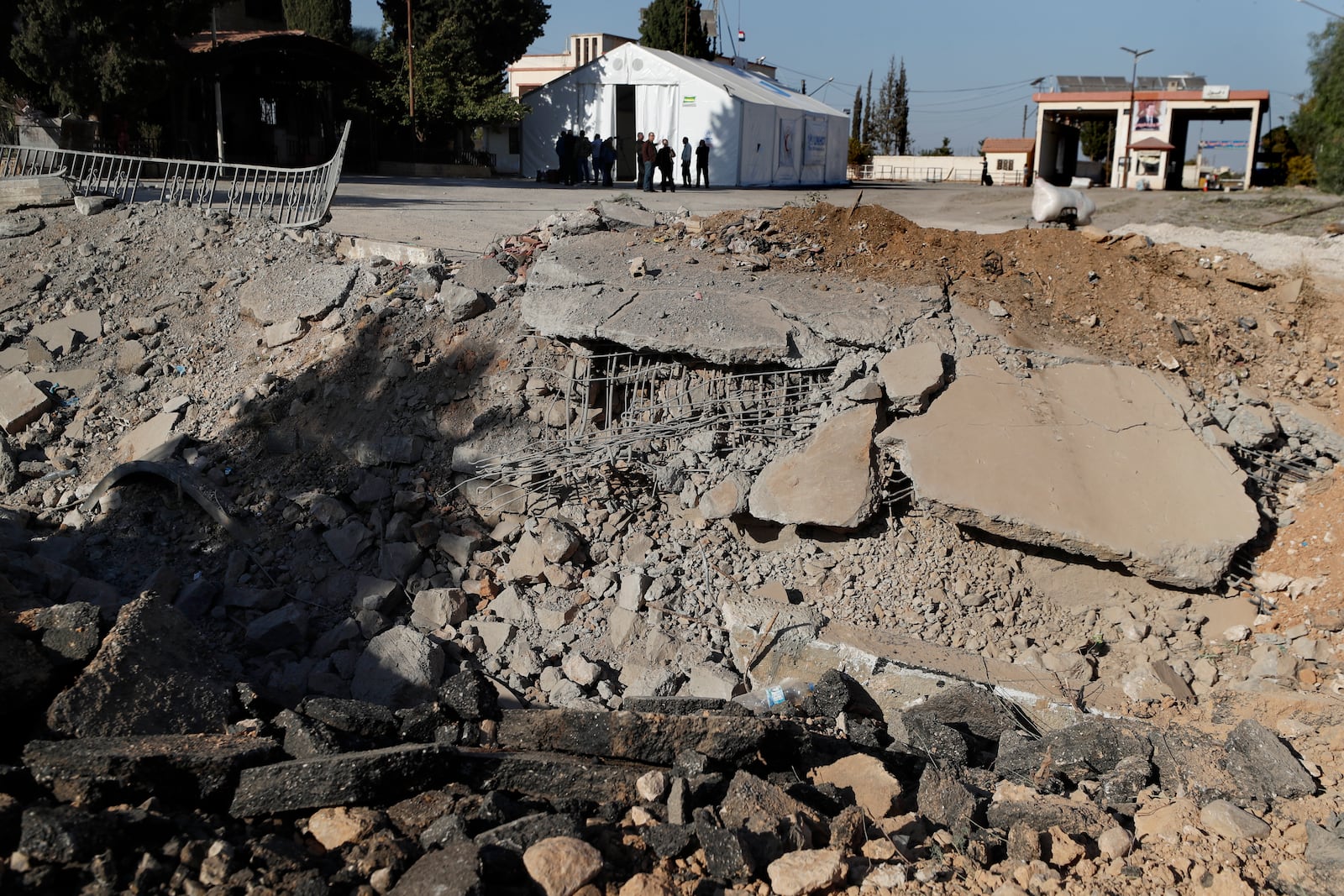 People gather near a crater caused by an Israeli airstrike, which blocks the road between the Lebanese and the Syrian crossing points, in Jousieh, Syria, Sunday, Oct. 27, 2024. (AP Photo/Omar Sanadiki)