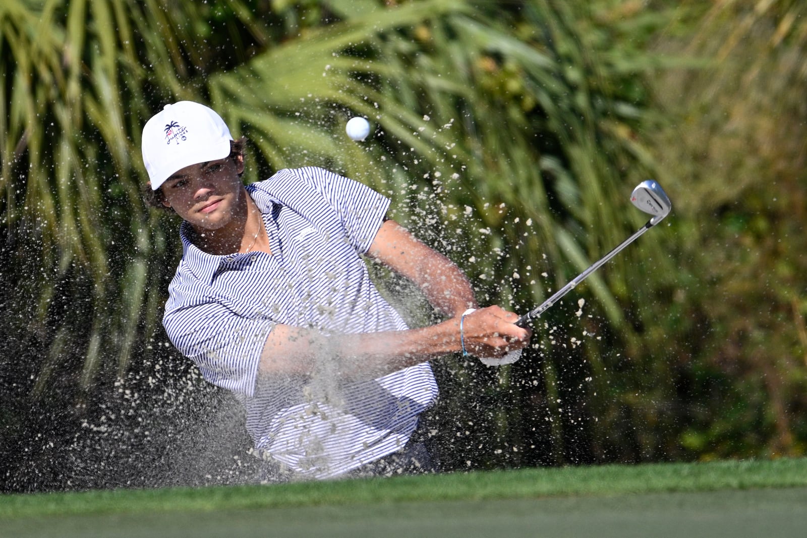 Charlie Woods hits out of a bunker onto the fourth green during the first round of the PNC Championship golf tournament, Saturday, Dec. 21, 2024 in Orlando. (AP Photo/Phelan M. Ebenhack)