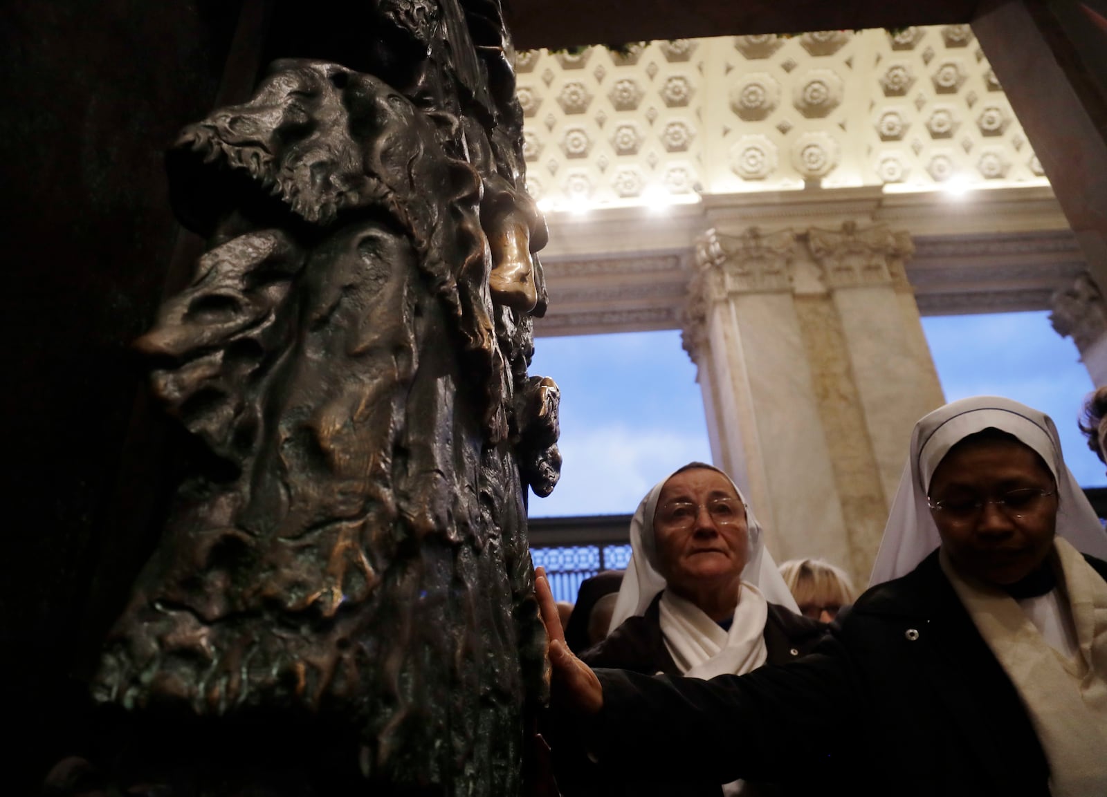 FILE - Nuns reach out to touch the the Holy Door of the St. John in Lateran basilica in Rome, Sunday, Nov. 13, 2016. (AP Photo/Gregorio Borgia, File)