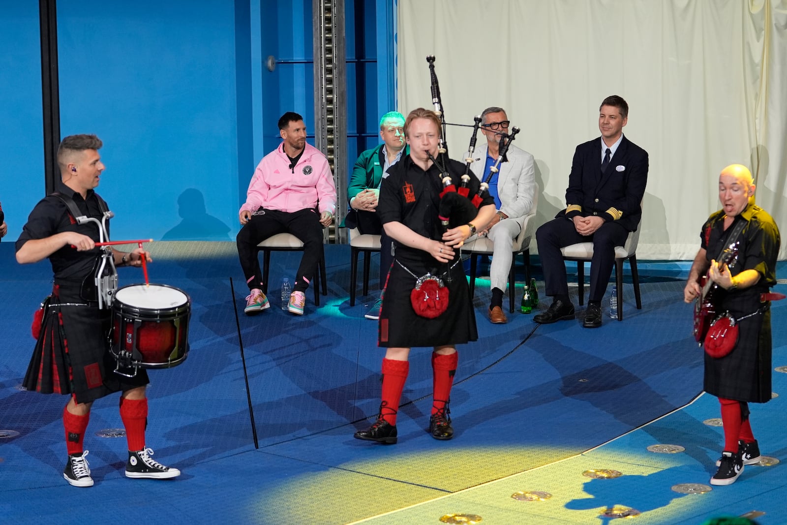 Inter Miami soccer player Lionel Messi, left, seated, watches as the Red Hot Chilli Pipers bagpipe band performs during a naming ceremony for Royal Caribbean International's new cruise ship, Icon of the Seas, Tuesday, Jan. 23, 2024, in Miami. Inter Miami CF has formed a partnership with the cruise line Royal Caribbean International. (AP Photo/Lynne Sladky)