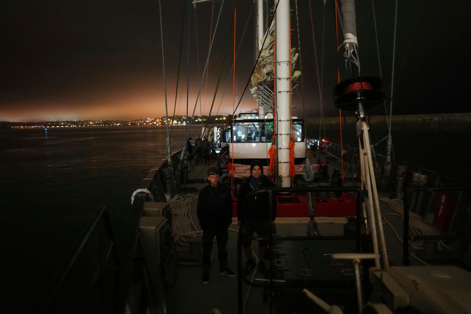 Sailors Tim Padellec, left, and Charles Mirassou stand on the deck of the sailboat 'Grain de Sail II' as he sails off Saint Malo, western France, Nov. 6, 2024. (AP Photo/Thibault Camus)