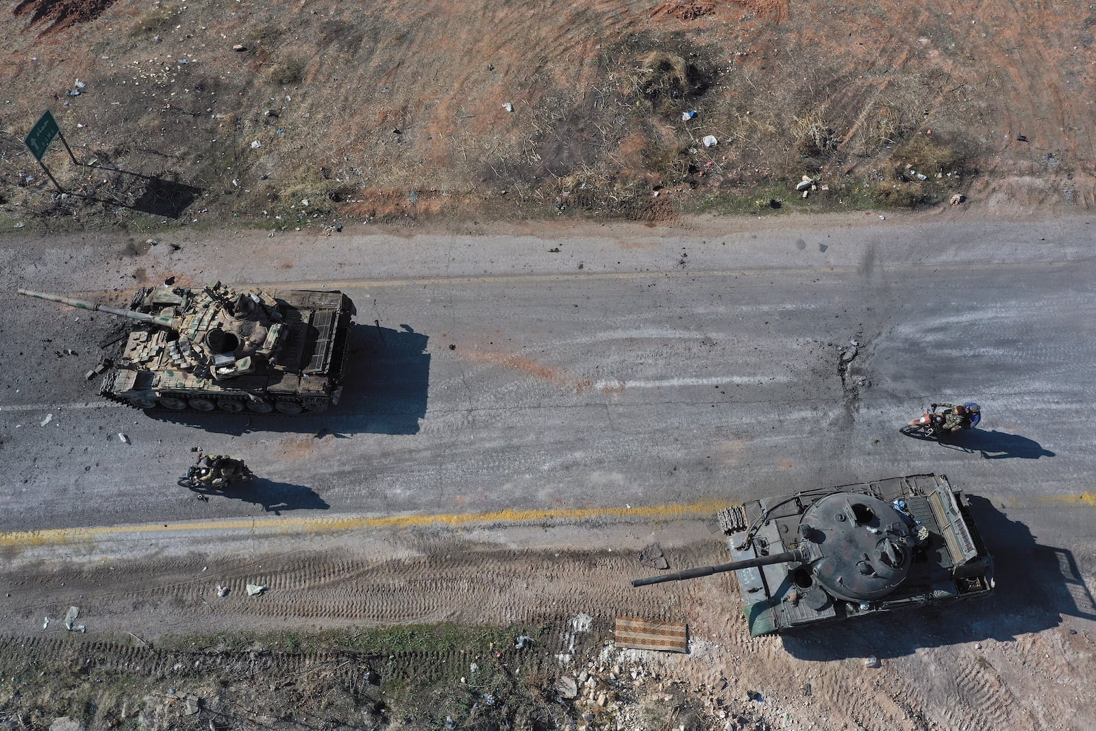 Syrian insurgents ride on motorcycles through abandoned Syrian army vehicles on a road in the outskirts of Hama, Syria, Tuesday Dec. 3, 2024.(AP Photo/Ghaith Alsayed)