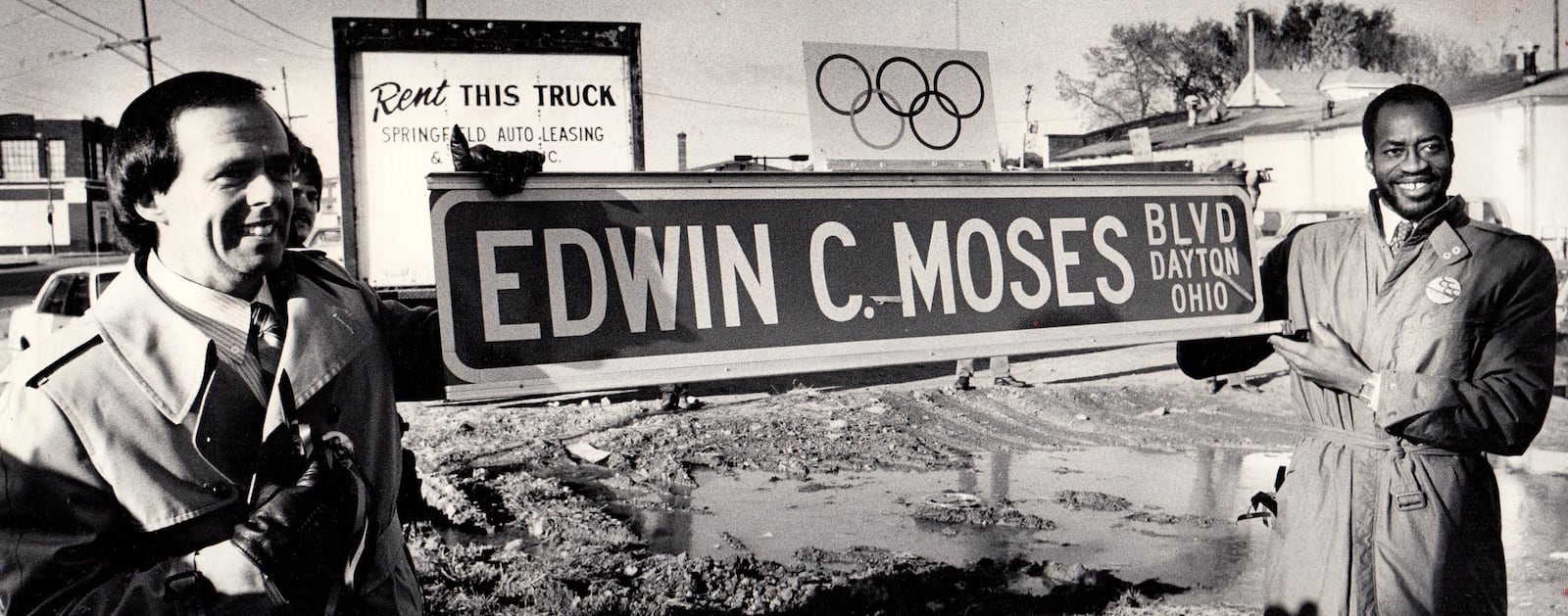 Mayor Paul Leonard (left) and Edwin Moses hold up an Edwin C. Moses Blvd. street sign for photographers during a ceremony renaming the street to honor the Olympic gold medal winner in 1984. DAYTON DAILY NEWS ARCHIVE