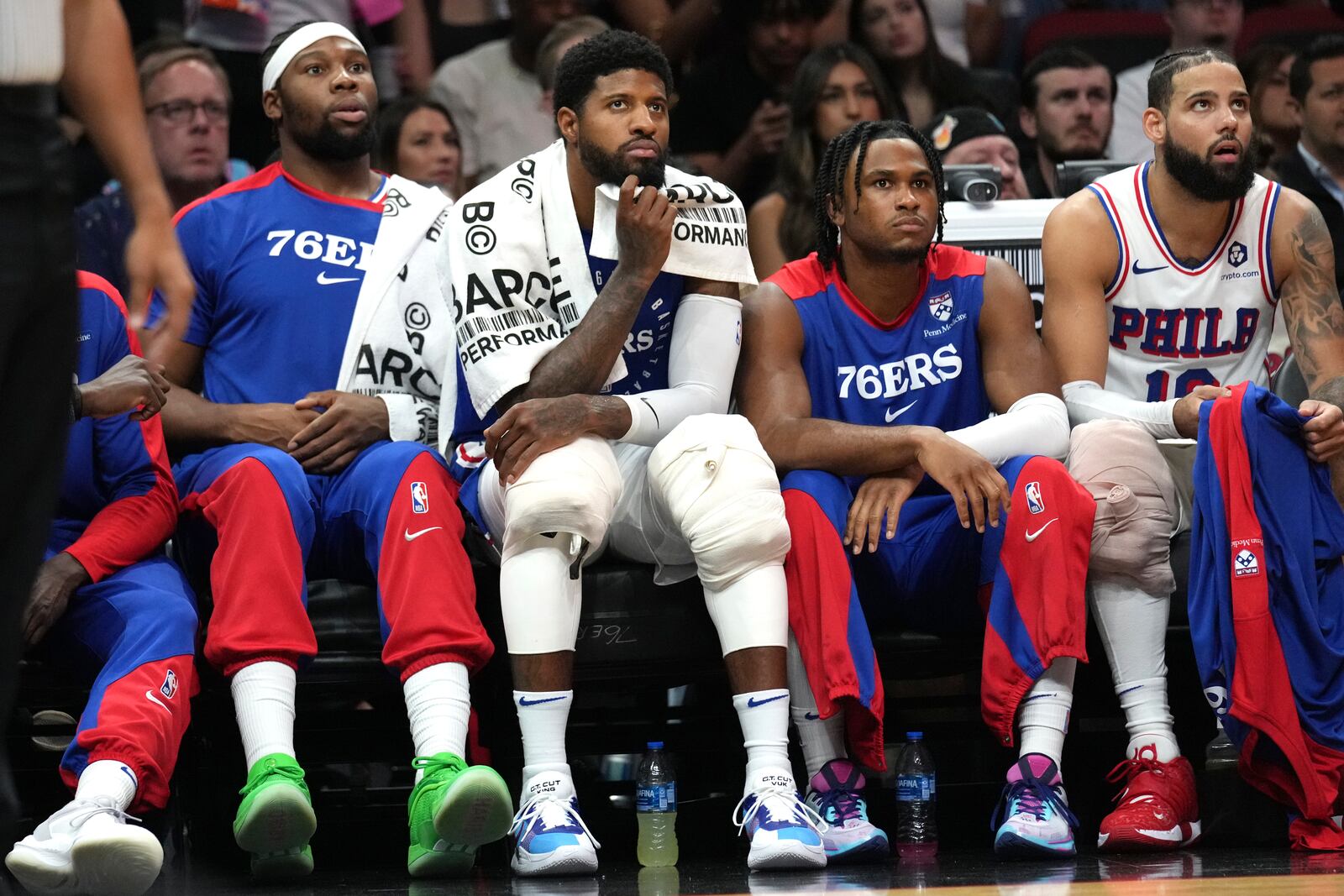 Philadelphia 76ers forward Paul George, second from left, and forward Caleb Martin, right, watch from the bench during the first half of an NBA basketball game against the Miami Heat, Monday, Nov. 18, 2024, in Miami. (AP Photo/Lynne Sladky)