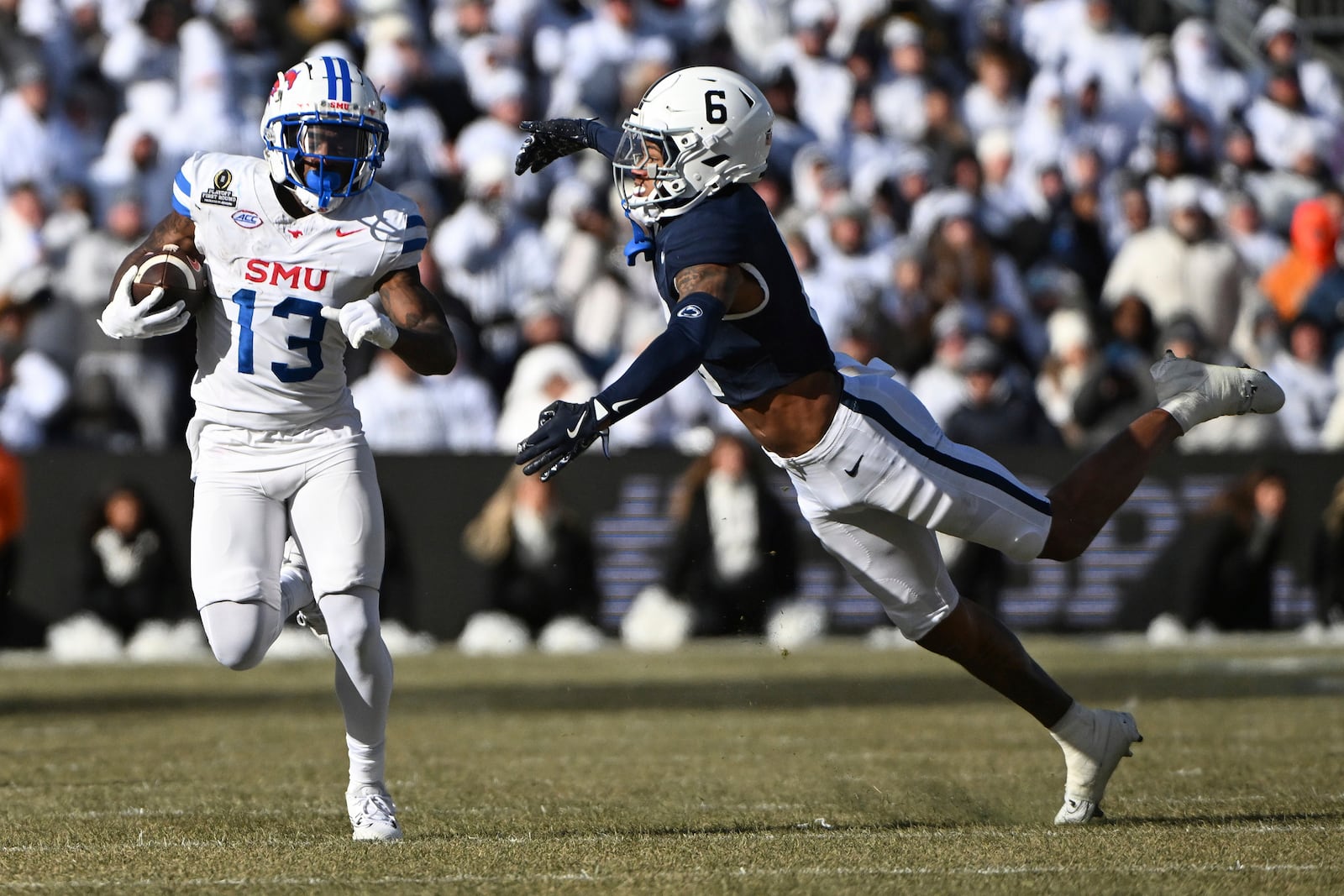 SMU wide receiver Roderick Daniels Jr. (13) looks to elude Penn State safety Zakee Wheatley (6) during the first half in the first round of the College Football Playoff, Saturday, Dec. 21, 2024, in State College, Pa. (AP Photo/Barry Reeger)