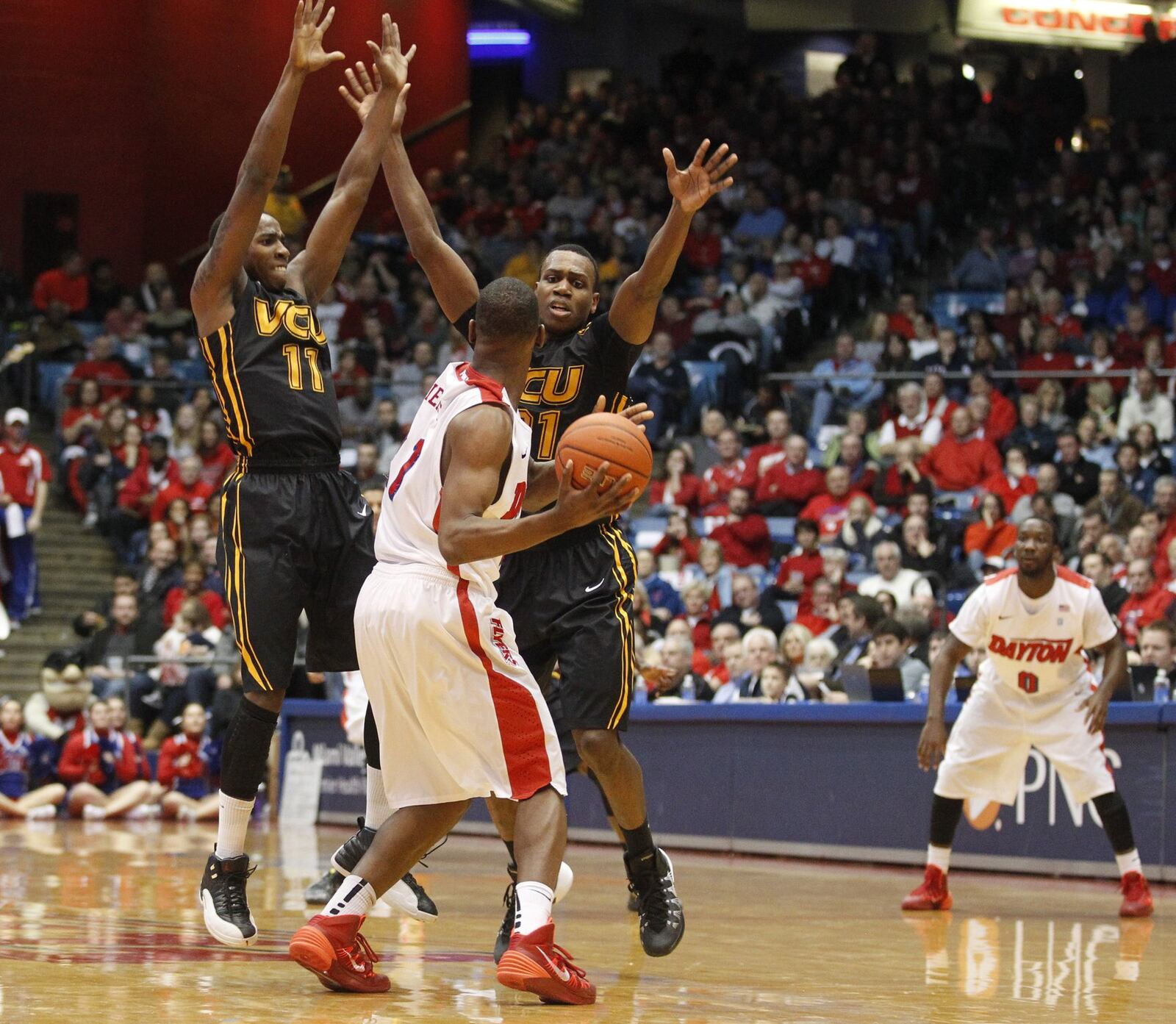 Dayton forward Dyshawn Pierre runs into pressure by Virginia Commonwealth’s Rob Brandenberg, left, and Treveon Graham, right, on Wednesday, Jan. 22, 2014, at UD Arena. David Jablonski/Staff