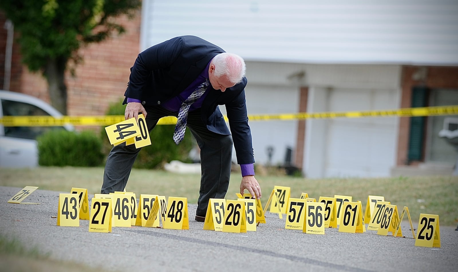 A member of the Miami Twp. police department collects evidence markers on Verdi Drive after a reported drive-by shooting Tuesday, Sept. 26, 2023. MARSHALL GORBY \STAFF