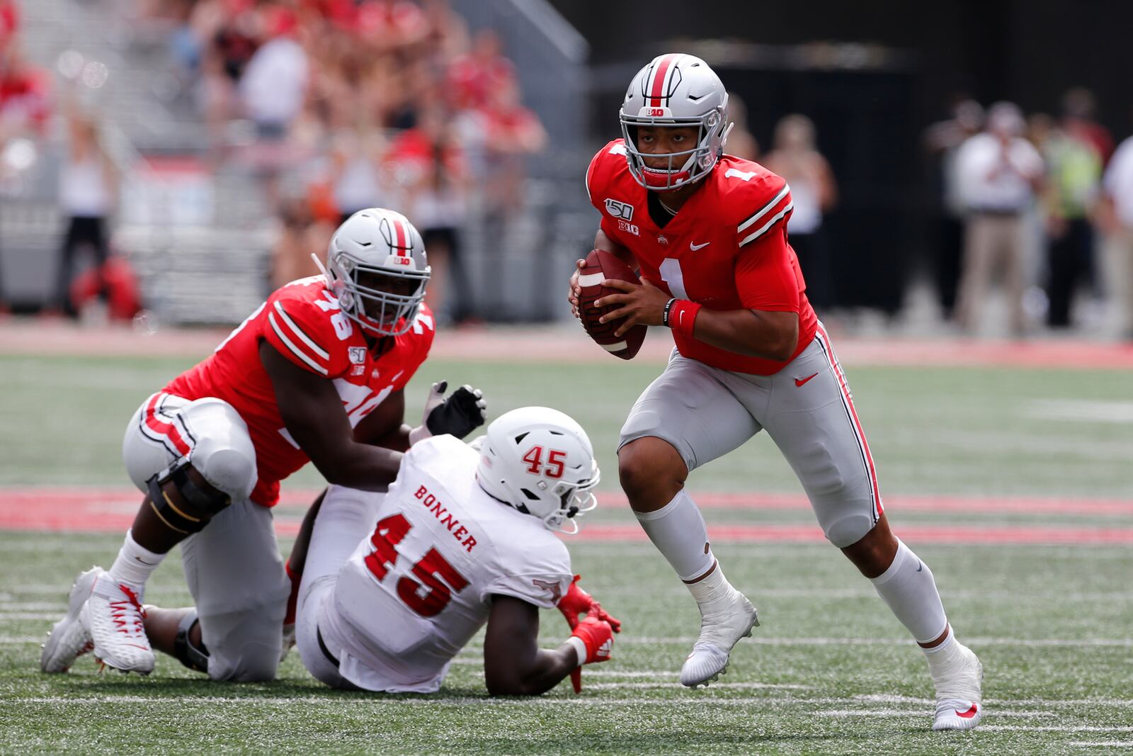 Ohio State quarterback Justin Fields, right, runs up field as teammate Nicholas Petit-Frere, left, blocks Florida Atlantic defensive end Tim Bonner during the second half of an NCAA college football game Saturday, Aug. 31, 2019, in Columbus, Ohio. Ohio State beat Florida Atlantic 45-21. (AP Photo/Jay LaPrete)