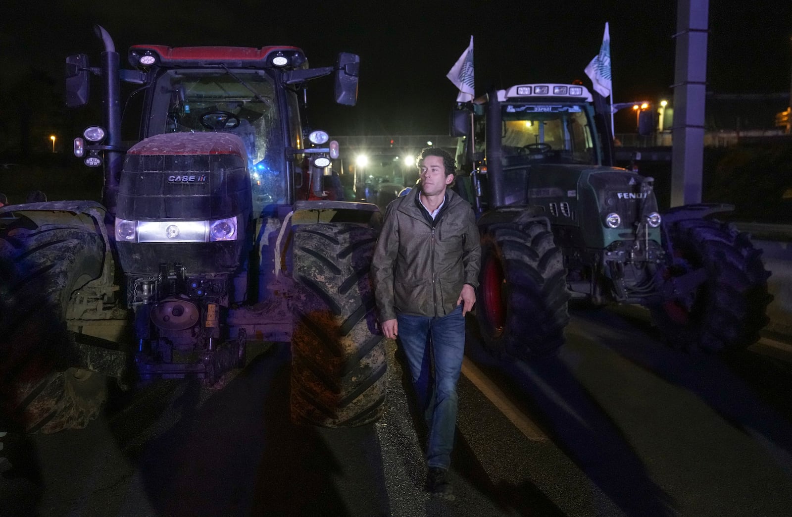 A farmers walks between tractors on a blocked highway in Velizy-Villacoublay, outside Paris, Sunday Nov. 17, 2024. (AP Photo/Michel Euler)