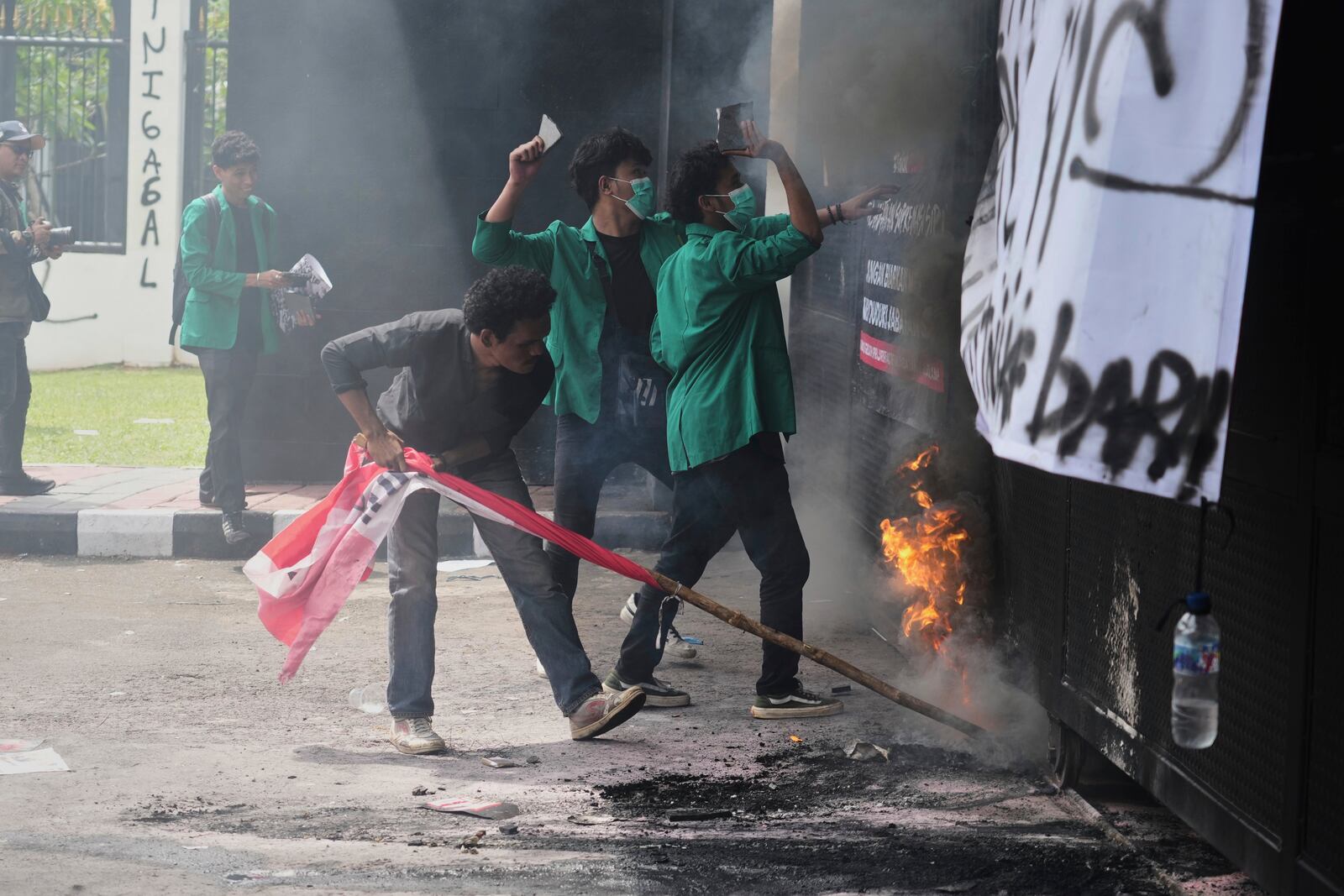 Student protesters burn a tire and throw objects at police officers during a rally against the passing of a new military law allowing active military personnel to hold more civilian posts, outside the parliament in Jakarta, Indonesia, Thursday, March 20, 2025. (AP Photo/Tatan Syuflana)