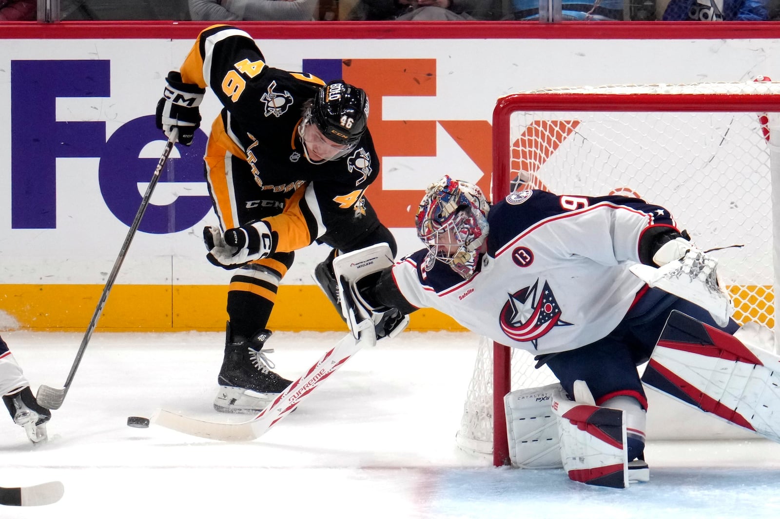 Columbus Blue Jackets goaltender Elvis Merzlikins, right, pokes the puck away from Pittsburgh Penguins' Blake Lizotte (46) during the period of an NHL hockey game in Pittsburgh, Tuesday, Jan. 7, 2025. (AP Photo/Gene J. Puskar)