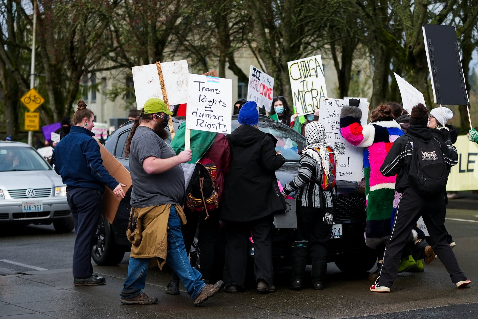 People stand in front of a driver attempting to continue past a protest against the Trump administration and Project 2025 near the Washington State Capitol building Wednesday, Feb. 5, 2025, in Olympia, Wash. (AP Photo/Lindsey Wasson)