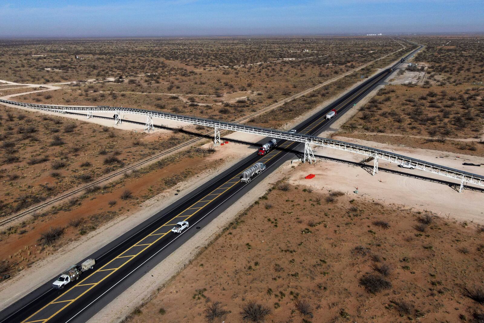 With the town of Jal, New Mexico, seen in the distance, a 42-mile conveyor belt by Atlas Energy carries sand needed for hydraulic fracturing Wednesday, Feb. 26, 2025, in Kermit, Texas. (AP Photo/Julio Cortez)