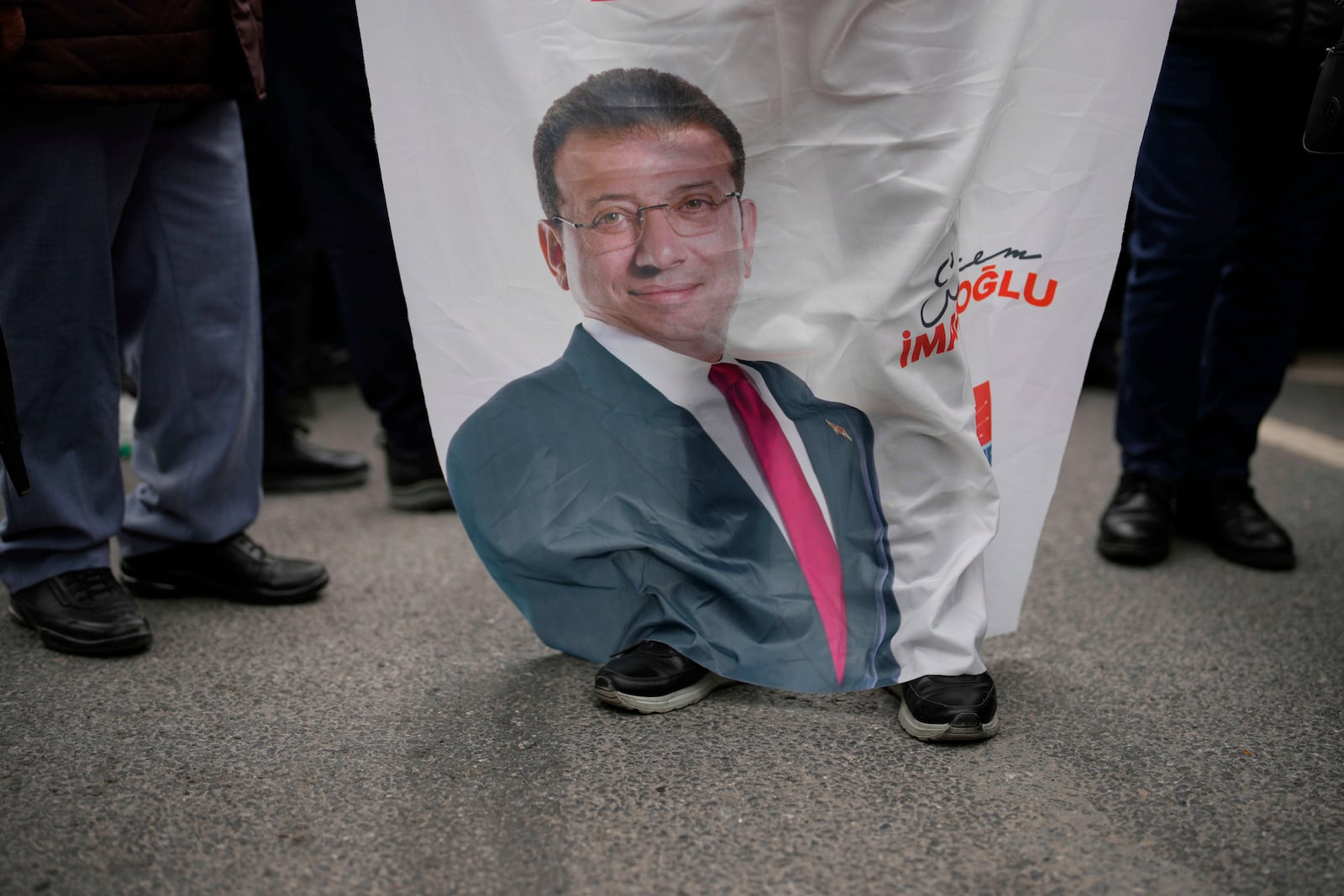 People gather, holding a banner featuring a photo of Istanbul Mayor Ekrem Imamoglu, to protest his arrest in Istanbul, Turkey, Wednesday, March 19, 2025. (AP Photo/Emrah Gurel)