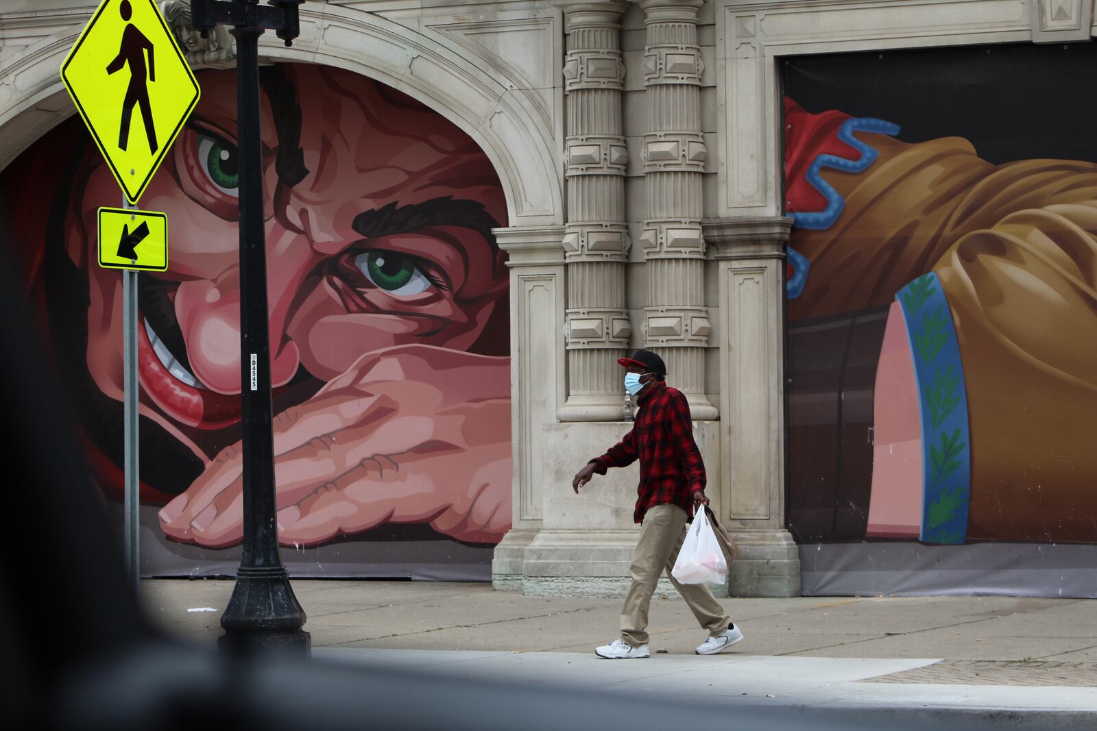 A man walks by the mural on the north end of the Dayton Arcade after finishing shopping at Stop-N-Save Foods on West Third Street in downtown Dayton. CORNELIUS FROLIK / STAFF