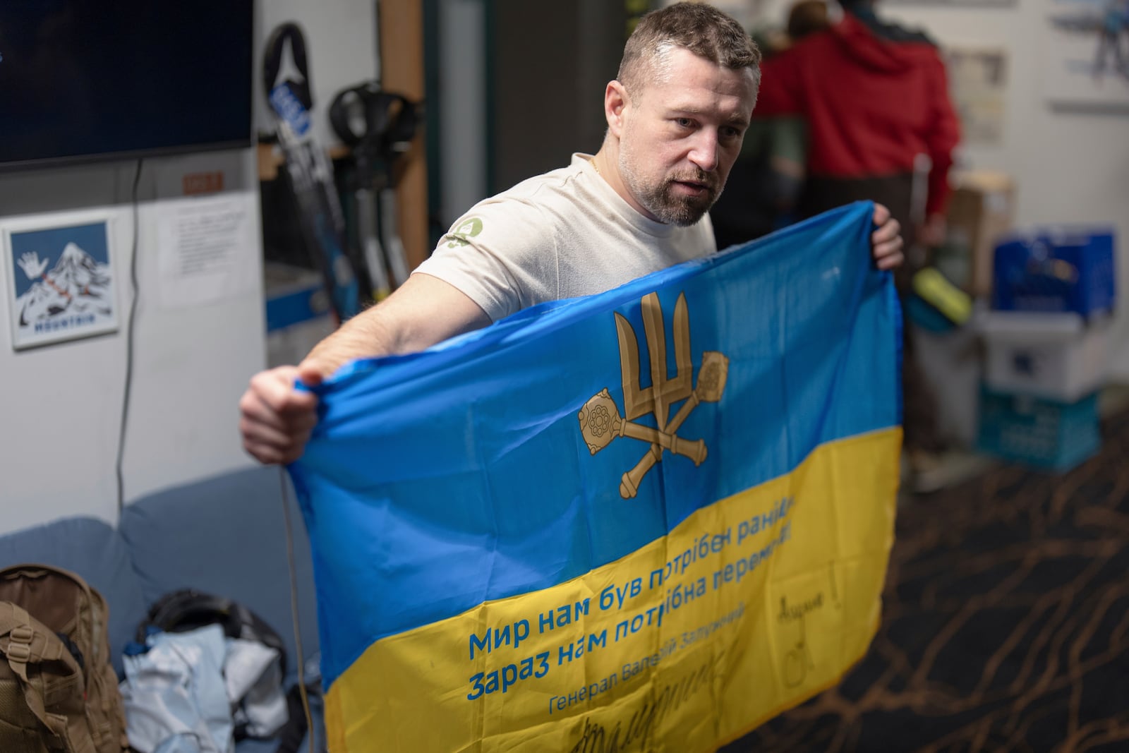 Ukrainian veteran Oleksandr Shvachka shows a Ukrainian flag that is signed to members of Oregon Adaptive Sports after a lesson on the three track skiing method at Hoodoo Ski Area in central Oregon on Thursday, March 6, 2025. (AP Photo/Jenny Kane)