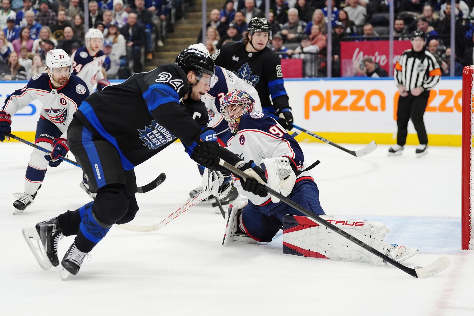 Toronto Maple Leafs' Auston Matthews (34) tries to get around Columbus Blue Jackets goaltender Elvis Merzlikins (90) during second period NHL hockey action in Toronto on Wednesday, January 22, 2025. (Frank Gunn/The Canadian Press via AP)