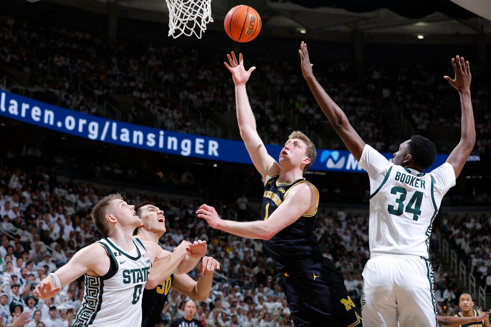 Michigan center Danny Wolf (1) shoots against Michigan State forwards Jaxon Kohler (0) and Xavier Booker (34) as Michigan center Vladislav Goldin, second from left, watches during the first half of an NCAA college basketball game, Sunday, March 9, 2025, in East Lansing, Mich. (AP Photo/Al Goldis)