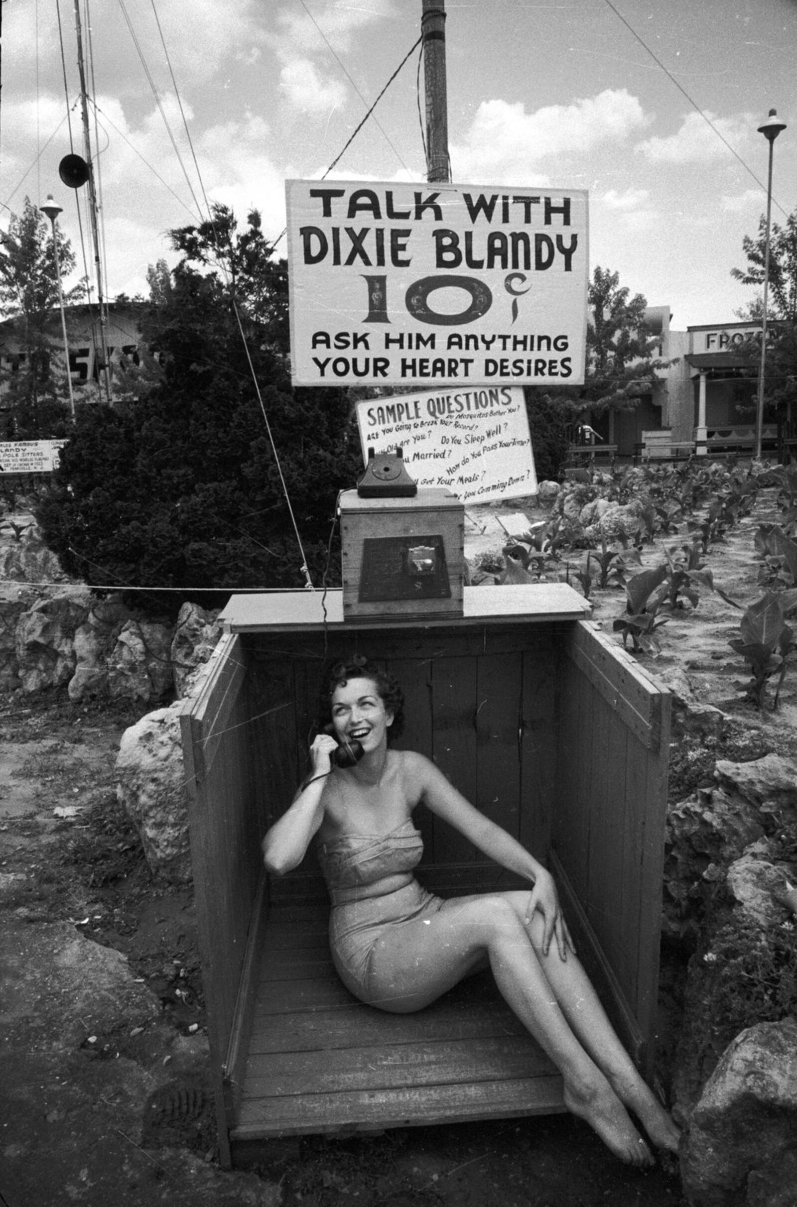 circa 1955: Kay Dugger calls champion flag pole sitter Dixie Blandy on the telephone. Mr Blandy has erected a sign at the base of his flagpole, inviting passers by to ask him a question while he balances above them. (Photo by Nocella/Three Lions/Getty Images)