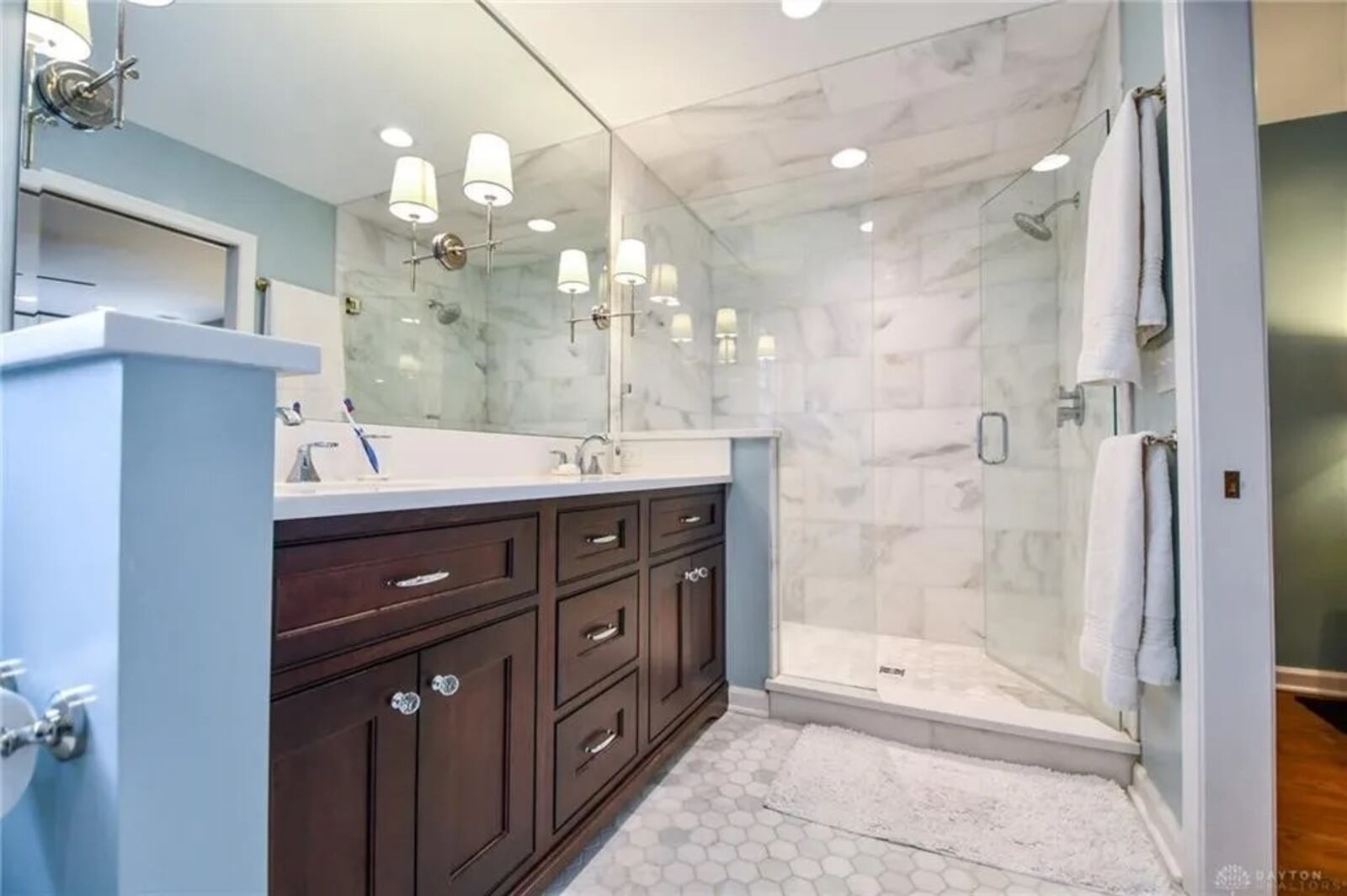 The walk-in shower has a ceramic-tile surround, seat and glass doors. 