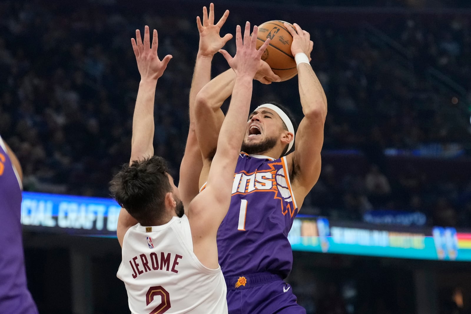 Phoenix Suns guard Devin Booker (1) shoots as Cleveland Cavaliers guard Ty Jerome (2) defends in the first half of an NBA basketball game, Monday, Jan. 20, 2025, in Cleveland. (AP Photo/Sue Ogrocki)