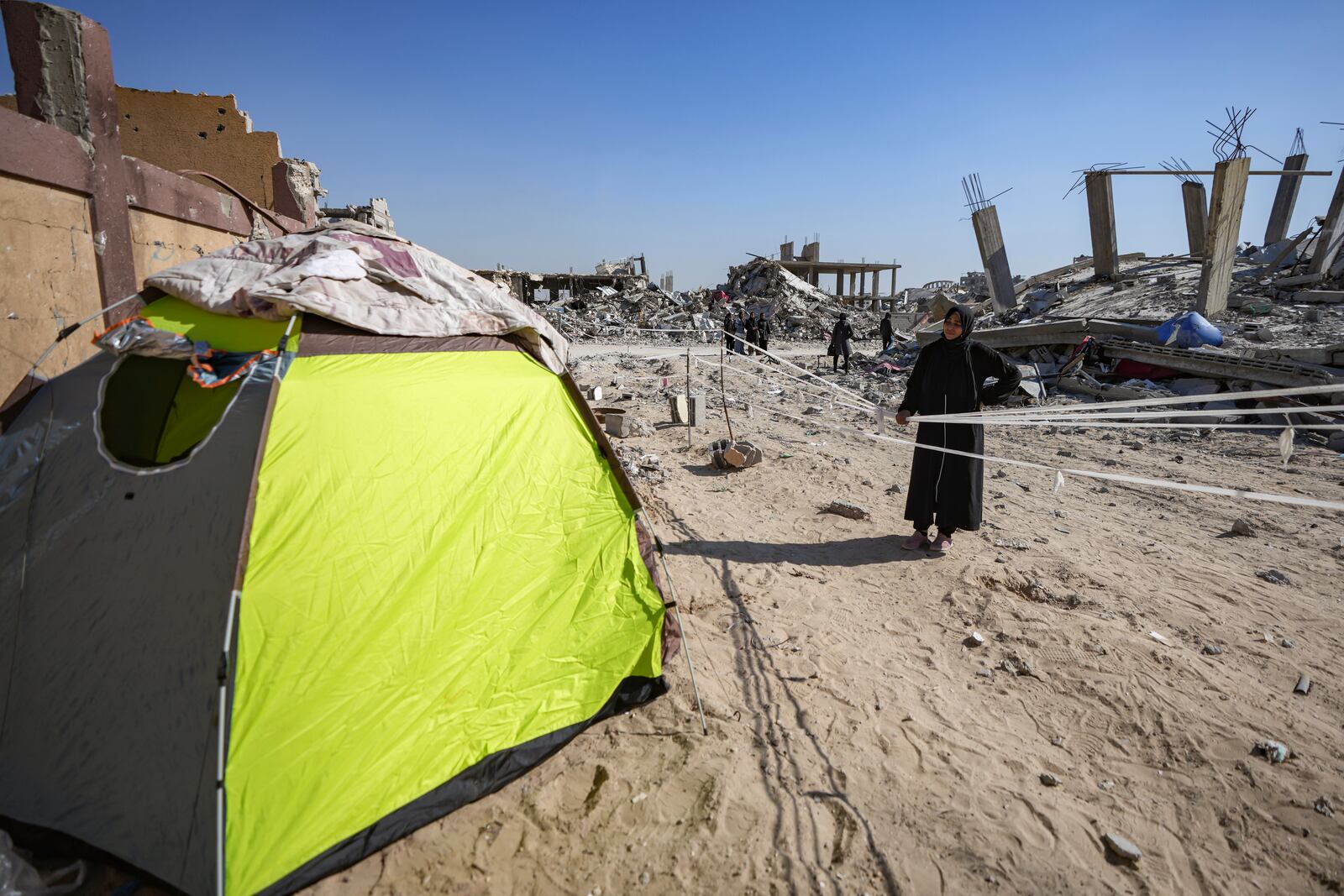 Manual Aslim stands next to a tent, she set up in front of her destroyed home, days after the ceasefire deal between Israel and Hamas came into effect, in Rafah, southern Gaza Strip, Tuesday, Jan. 21, 2025. (AP Photo/Abdel Kareem Hana)