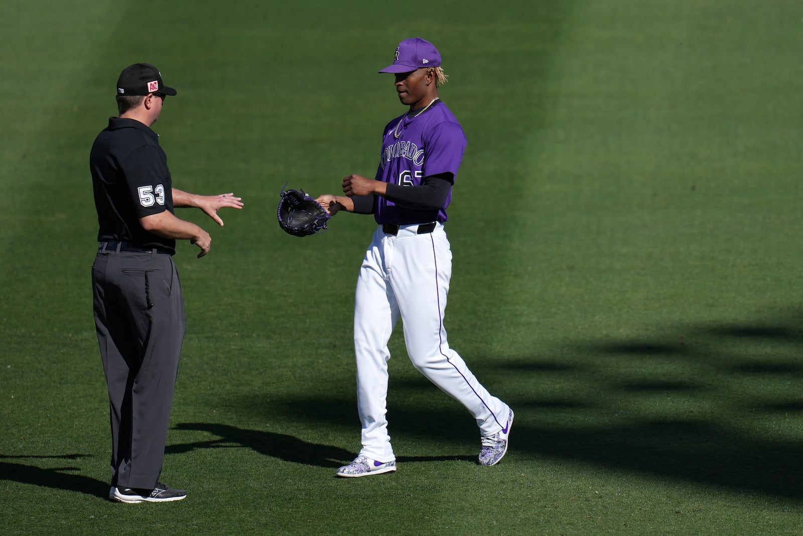 MLB umpire Macon Hammond (53) checks the glove of Colorado Rockies pitcher Jefry Yan, right, during the seventh inning of a spring training baseball game against the Seattle Mariners, Sunday, March 2, 2025, in Scottsdale, Ariz. (AP Photo/Ross D. Franklin)