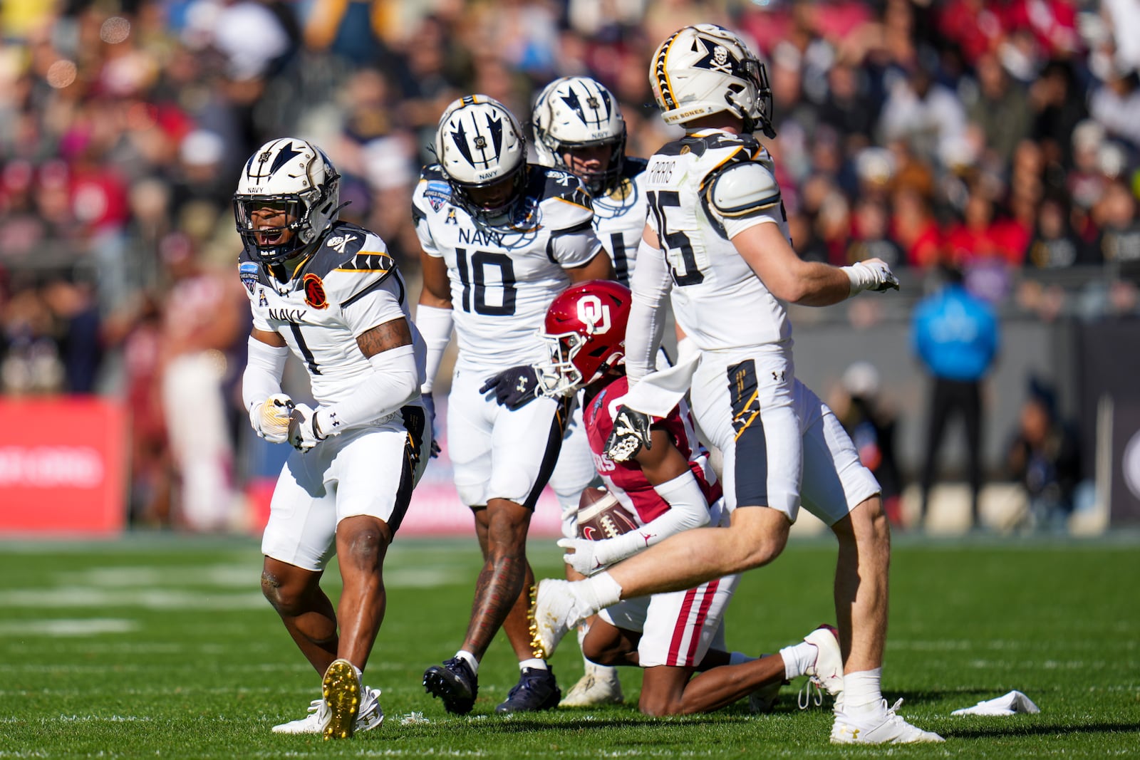 Navy cornerback Dashaun Peele (1) reacts after making a tackle against Oklahoma wide receiver Zion Ragins, bottom right, during the first half of the Armed Forces Bowl NCAA college football game, Friday, Dec. 27, 2024, in Fort Worth, Texas. (AP Photo/Julio Cortez)