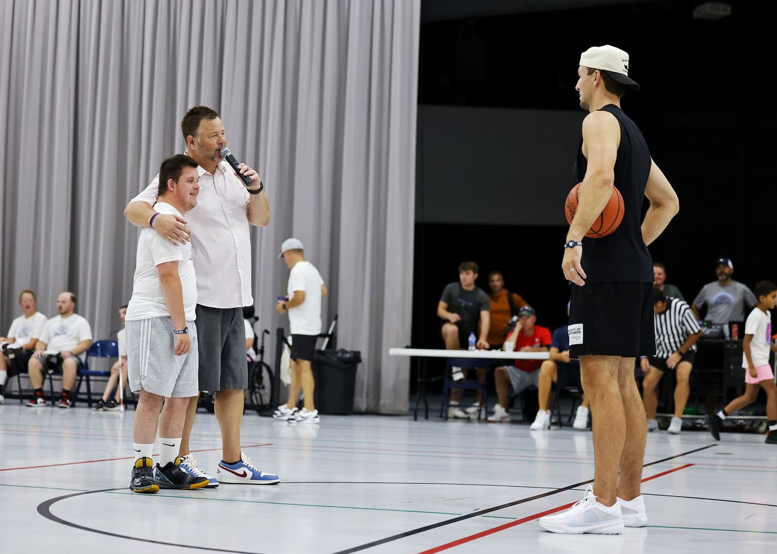 Berachah Church pastor Lamar Ferrell stand with Luke Atkinson during a halftime basketball challenge with NBA player Luke Kennard during "One Special Game" basketball game held for those with special needs during the Luke Kennard basketball camp at Camp Chautauqua Saturday, July 20, 2024. Camp attendees cheered on the players during the event. NICK GRAHAM/STAFF